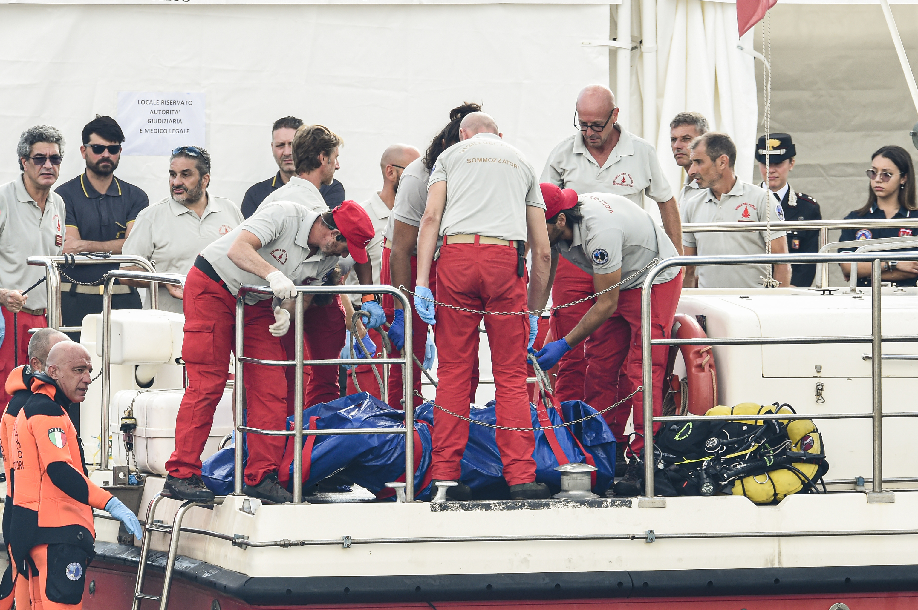 Italian firefighter divers bring ashore in a plastic bag the body of one of the victims of a shipwreck, in Porticello