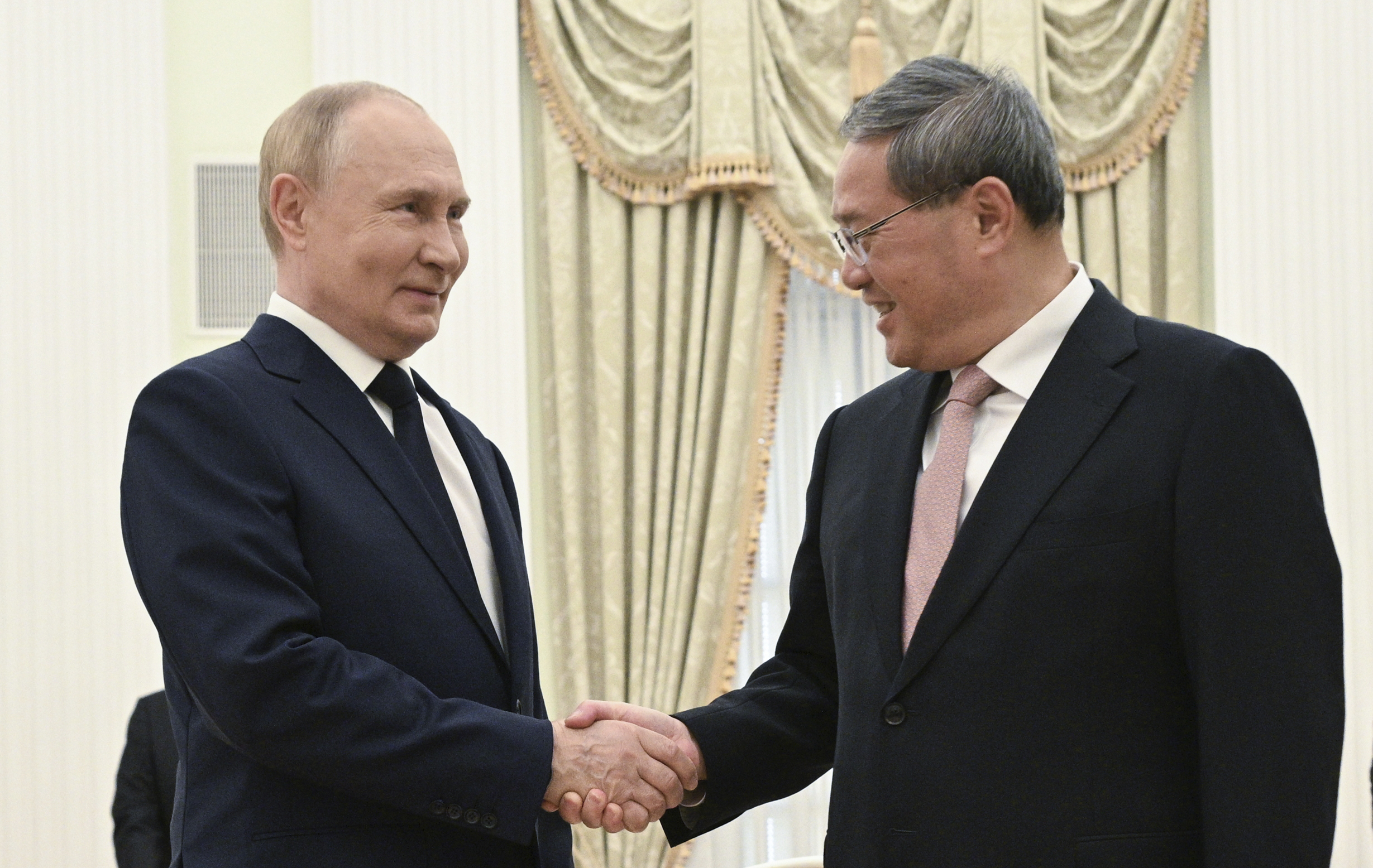 Russian President Vladimir Putin, left, and Chinese Premier Li Qiang shake hands during their meeting at the Kremlin in Moscow