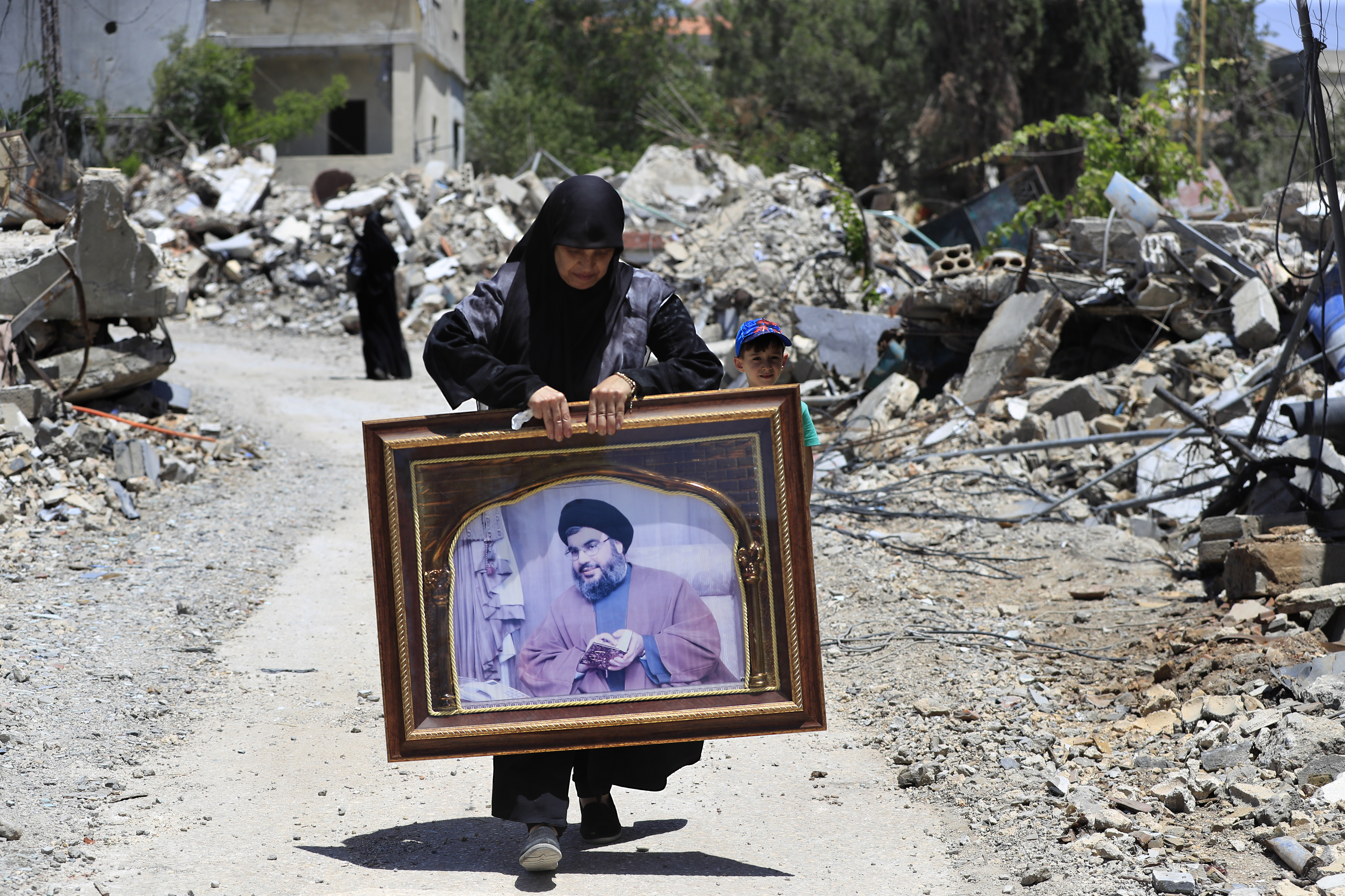 A woman carries a frame that shows a portrait for Hezbollah leader Sayyid Hassan Nasrallah