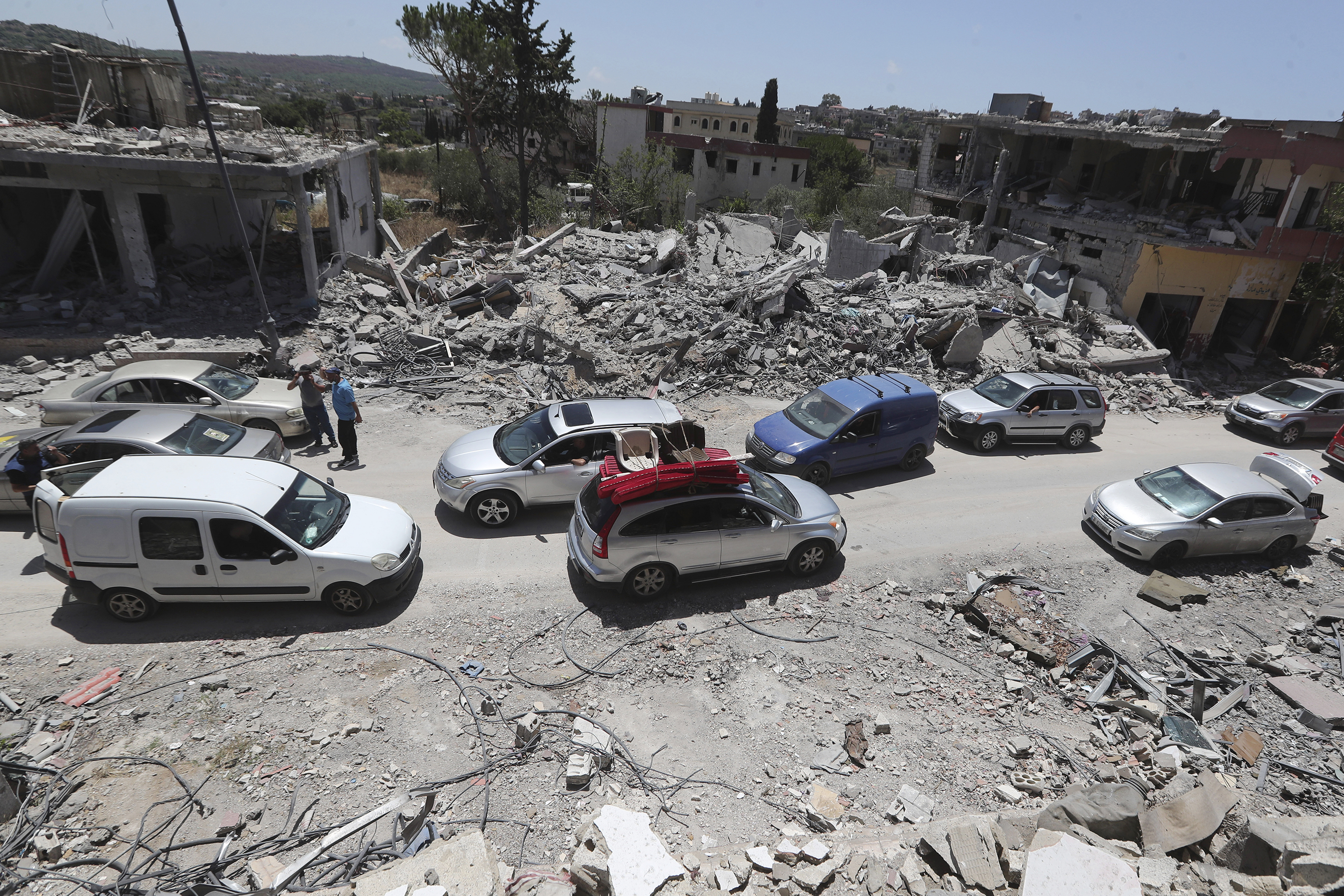 People inspect their destroyed houses that were hit by an Israeli airstrike, in Aita al-Shaab village