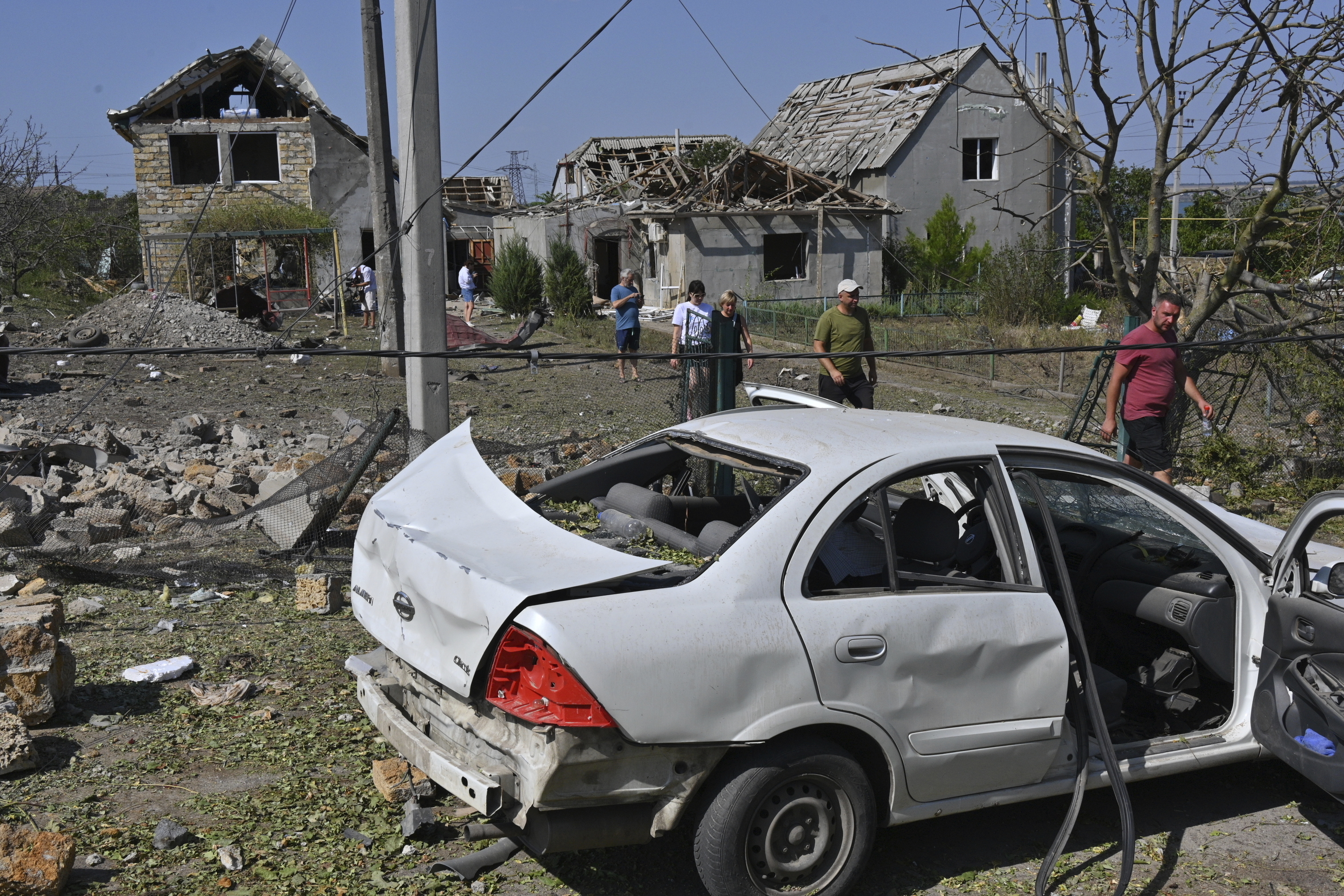 People walk in front of their damaged houses after Russian rocket attack in Usatove village near Odesa