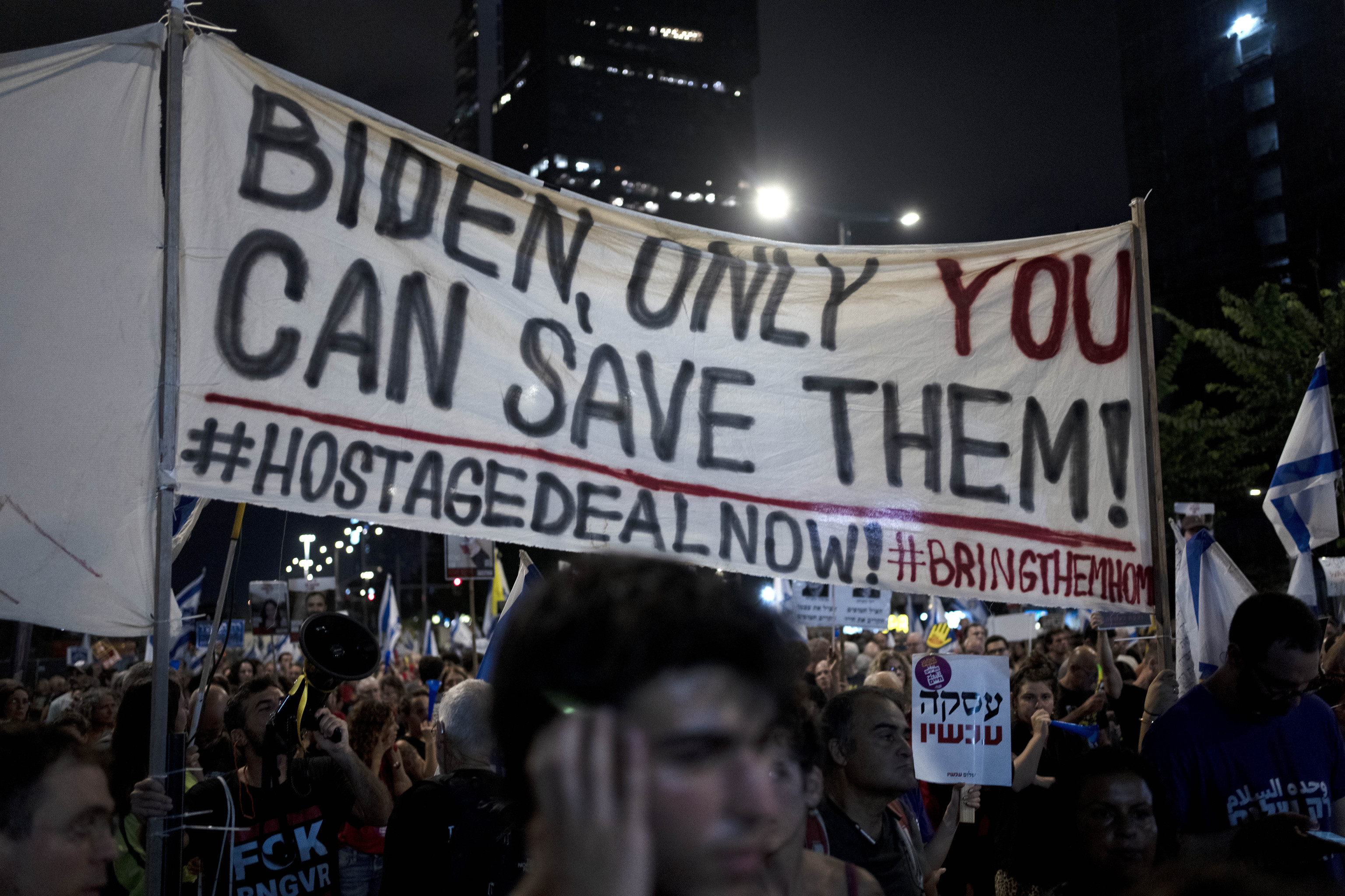 Activists carry a message for U.S. President Joe Biden as relatives of hostages held by Hamas