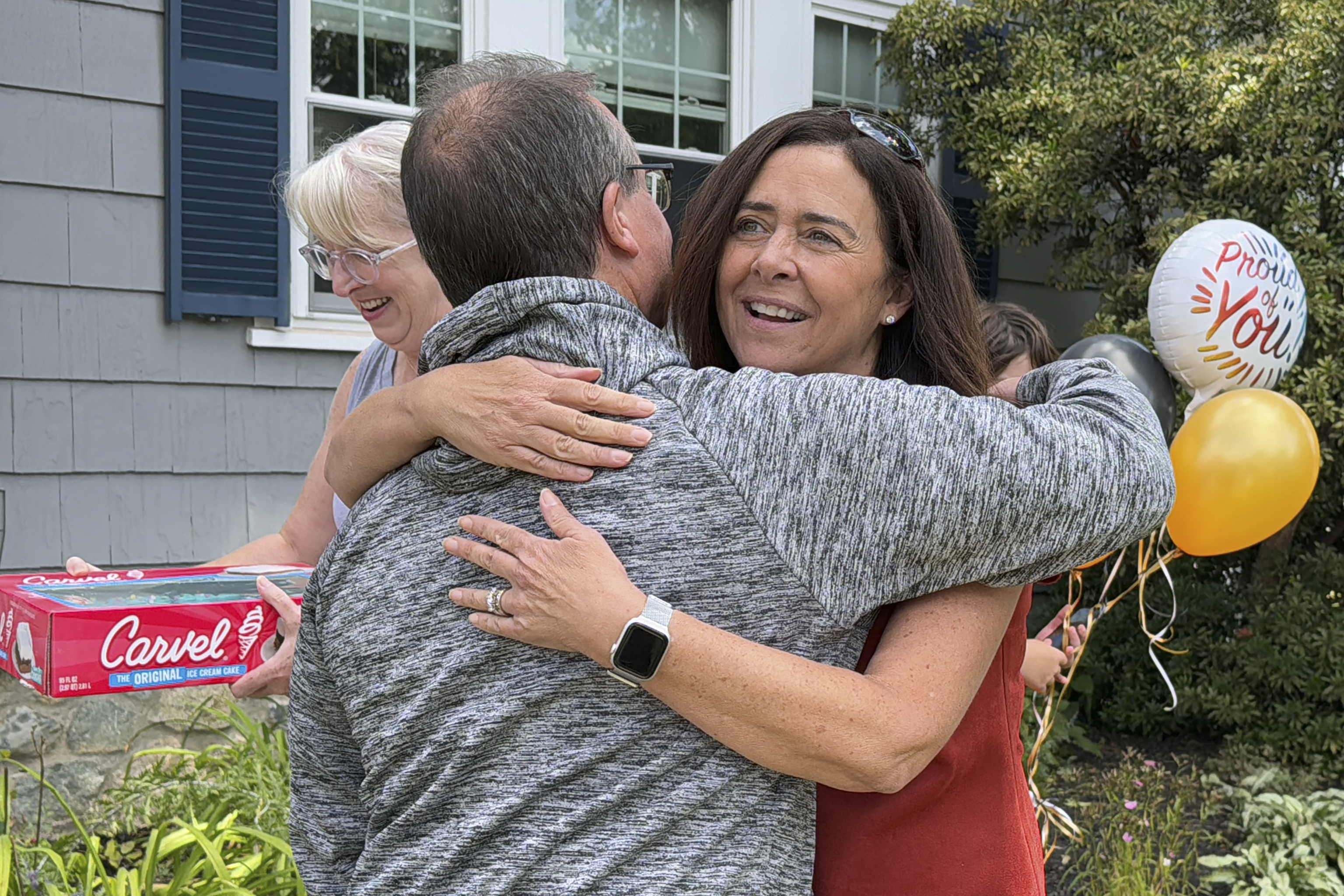 Lori Talanian, right, director of corporate partnerships at Ira Cars, hugs John Quill, center, director and coach of the Boston Bear Cubs hockey team