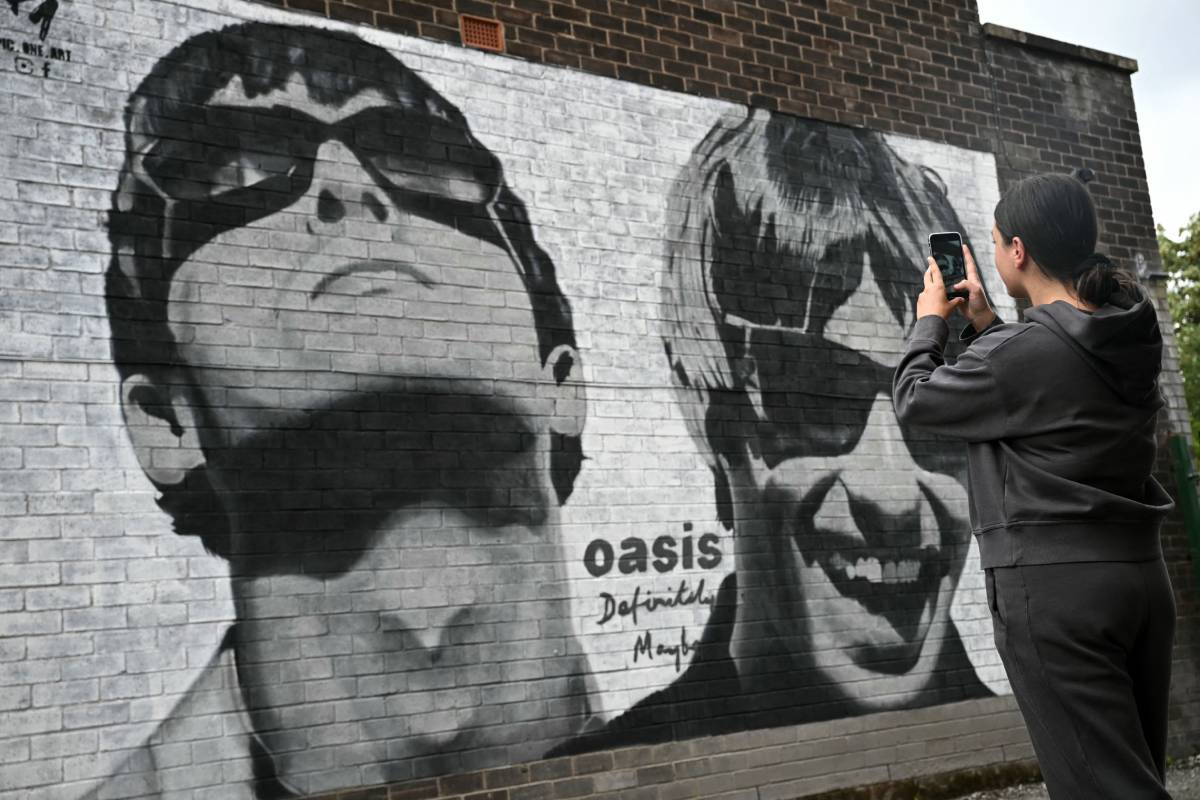 La fan Emily McShane, toma una fotografa de una nueva obra de arte callejero que representa a Liam y Noel Gallagher de Oasis, creada por Manchester.