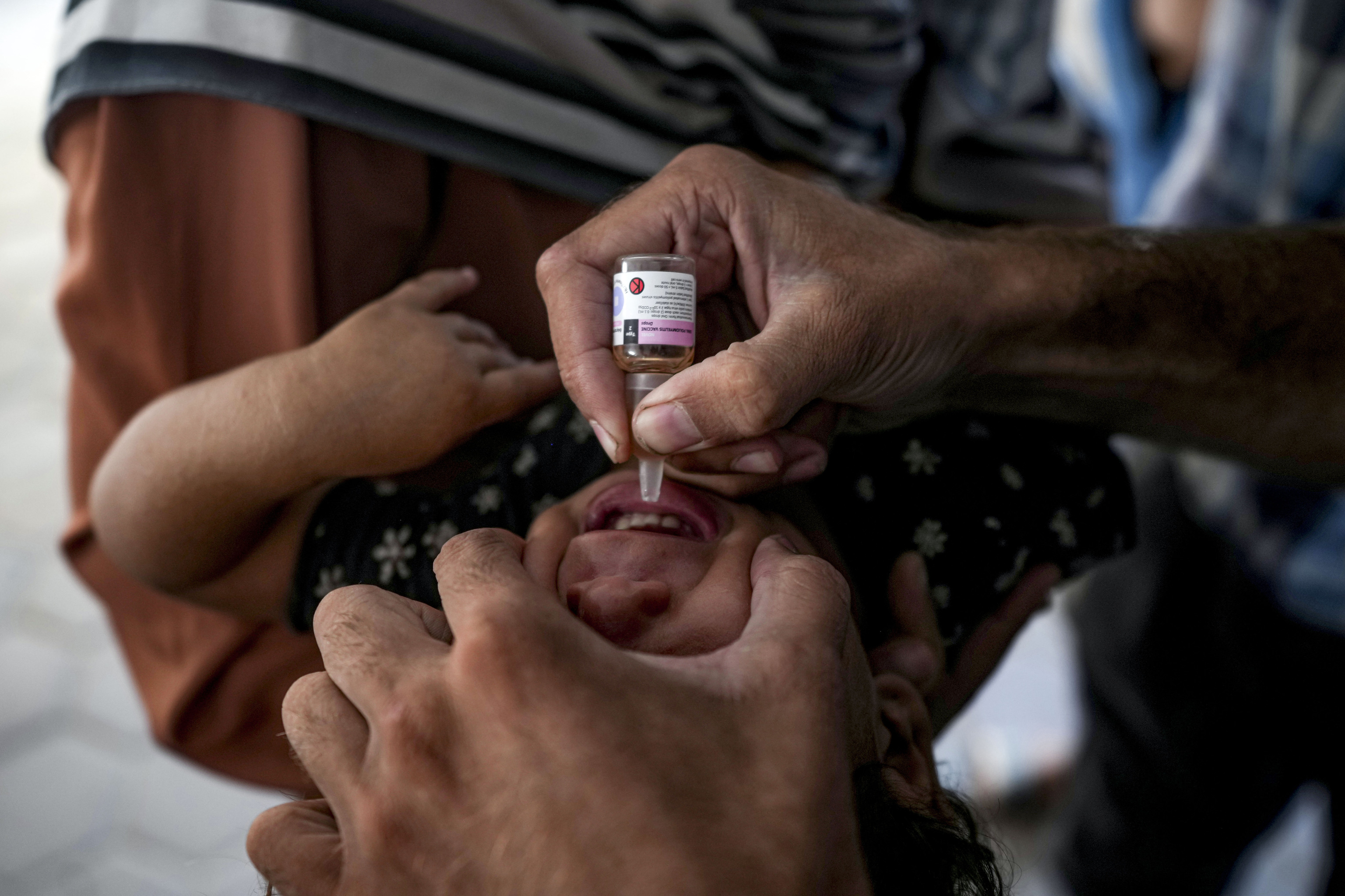 A health worker administers a polio vaccine to a child