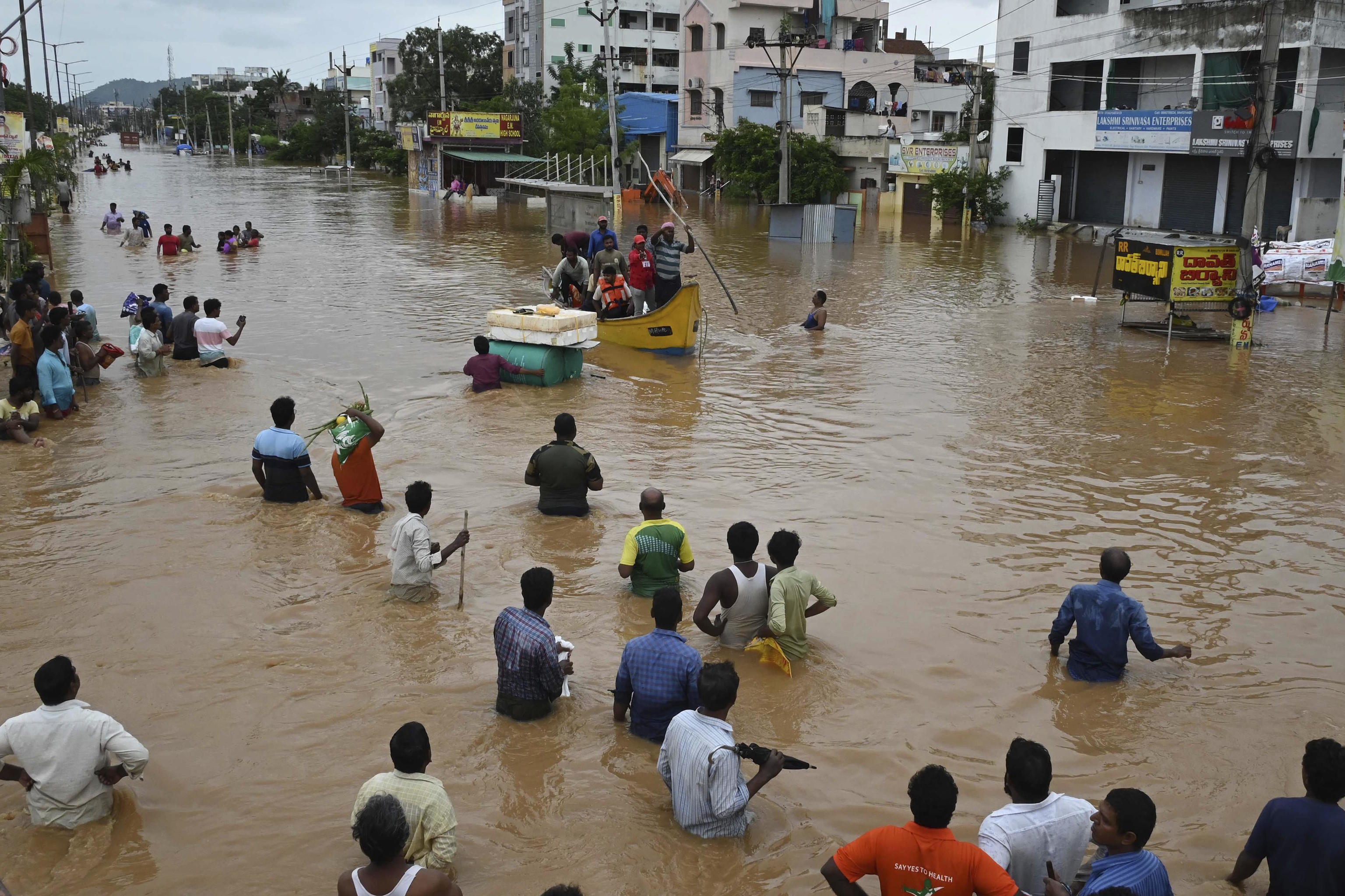 People wade through a flooded road after heavy rains in Vijayawada, India.