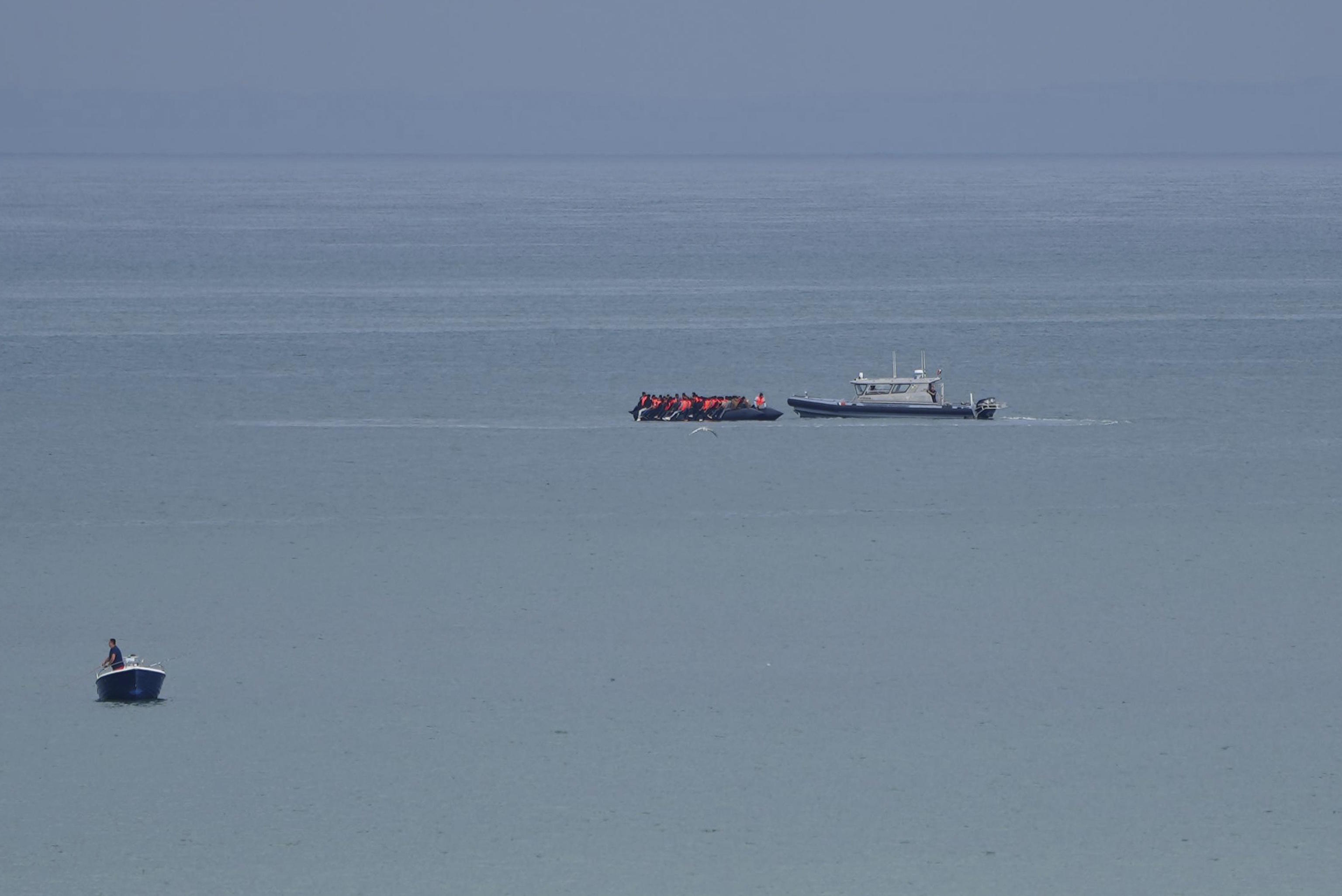 A boat is escorted by a vessel from the French Gendarmerie Nationale.