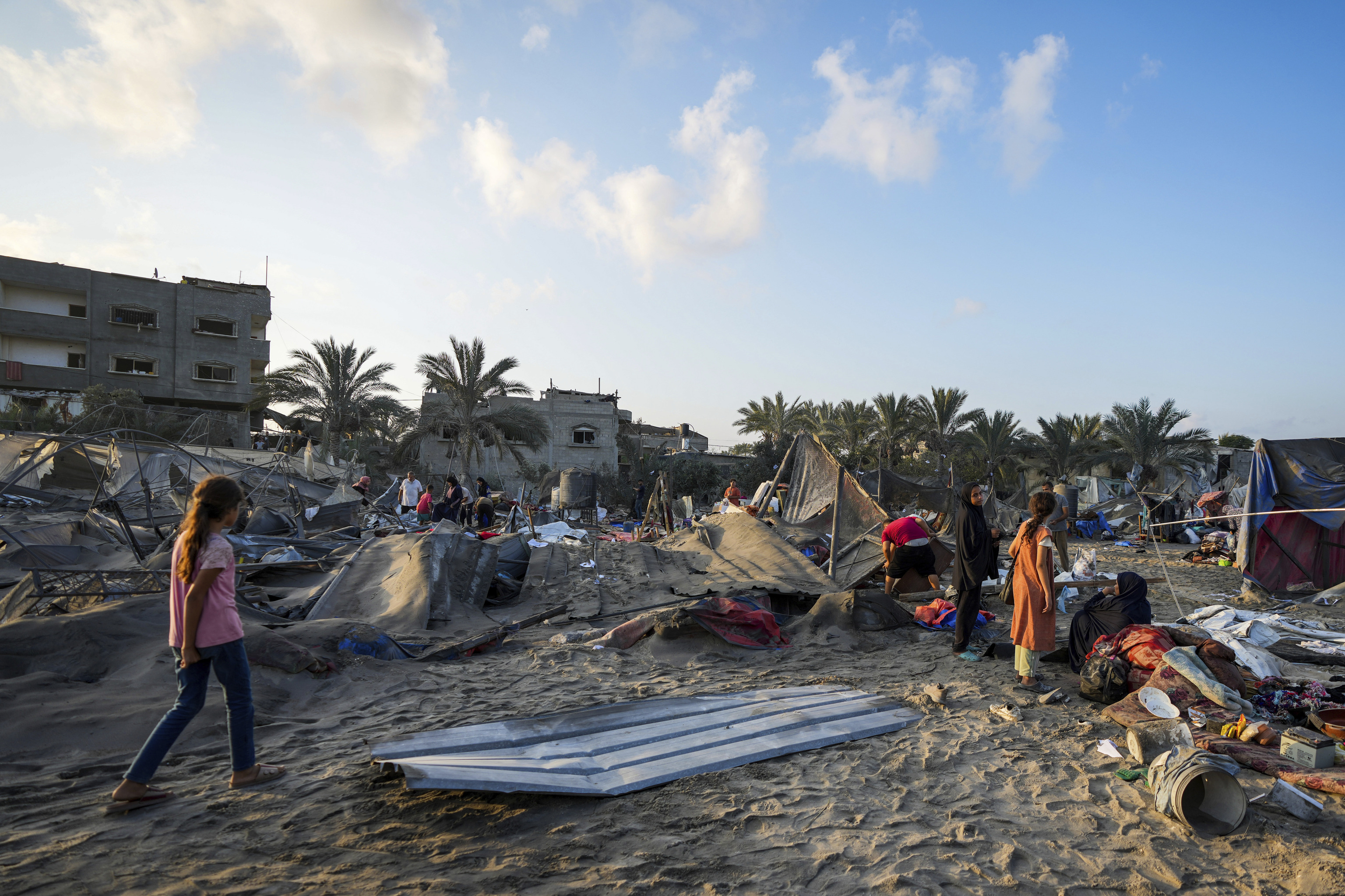 Palestinians look at the destruction after an Israeli airstrike on a crowded tent camp housing Palestinians.