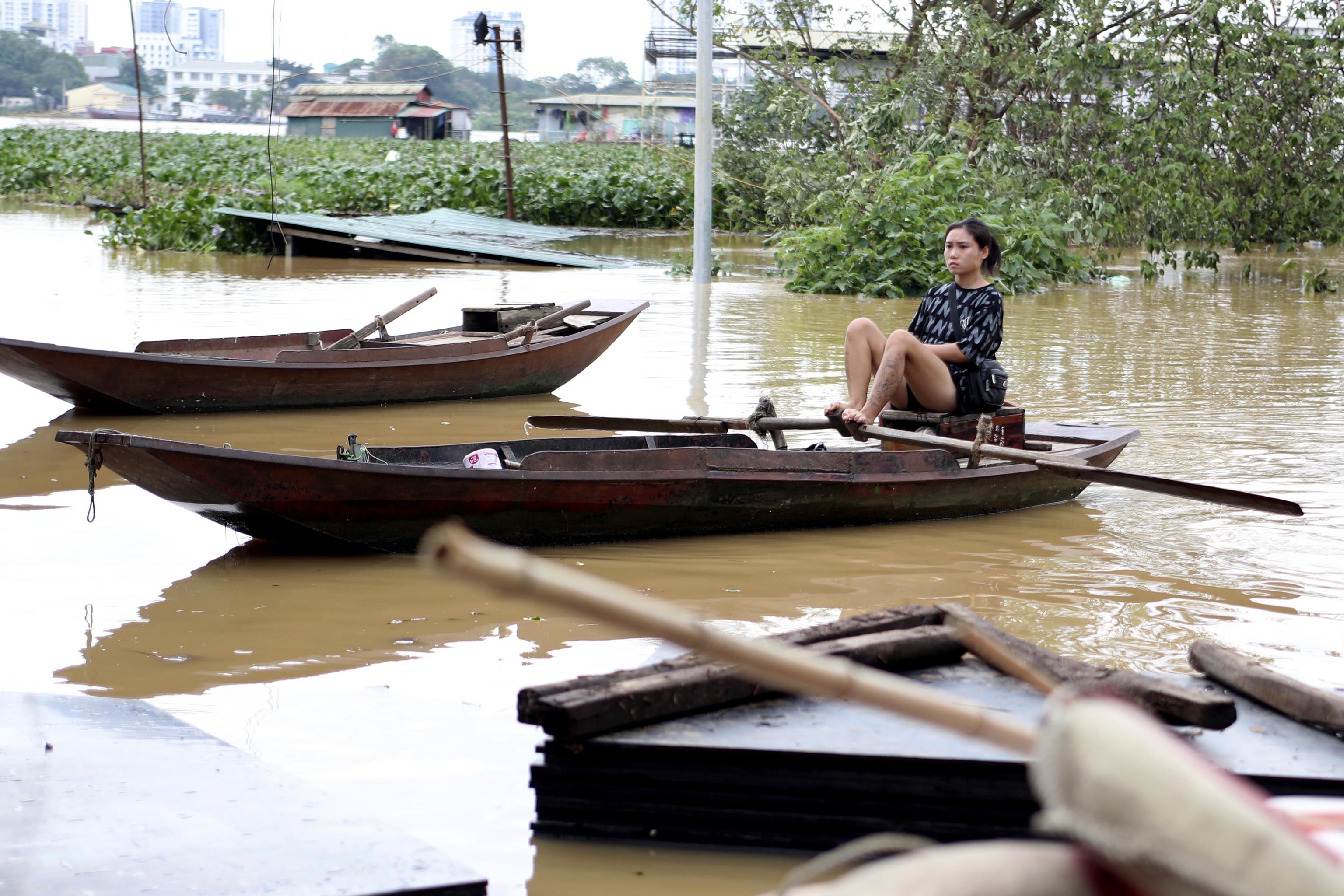 A woman paddles a boat on a flooded street, following Typhoon Yagi.