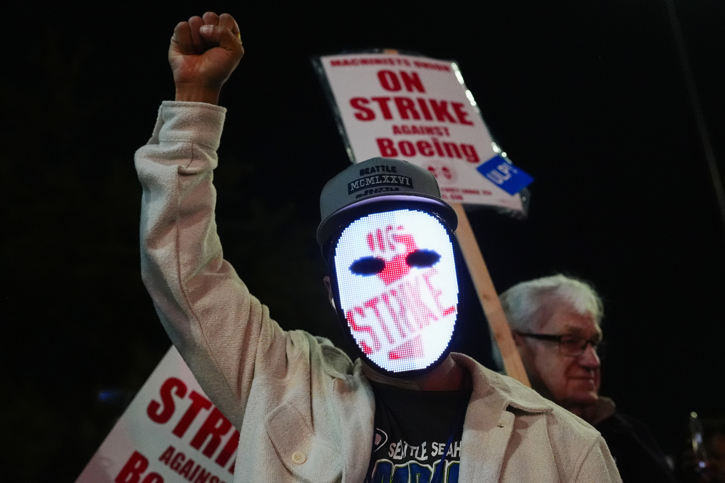 A Boeing worker wears a mask with a digital "strike" sign