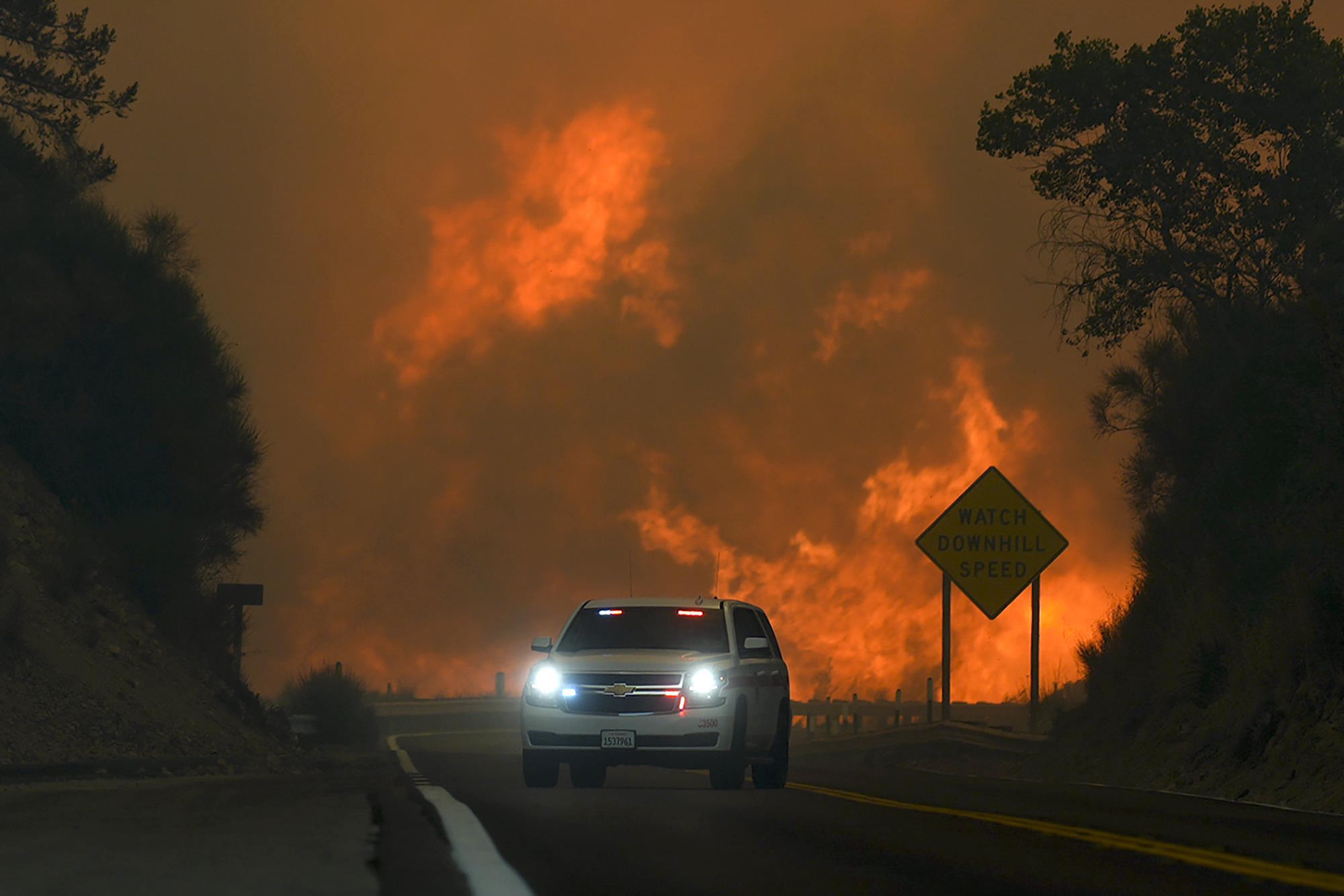 The Line Fire jumps Highway 330 as an emergency vehicle is driven.