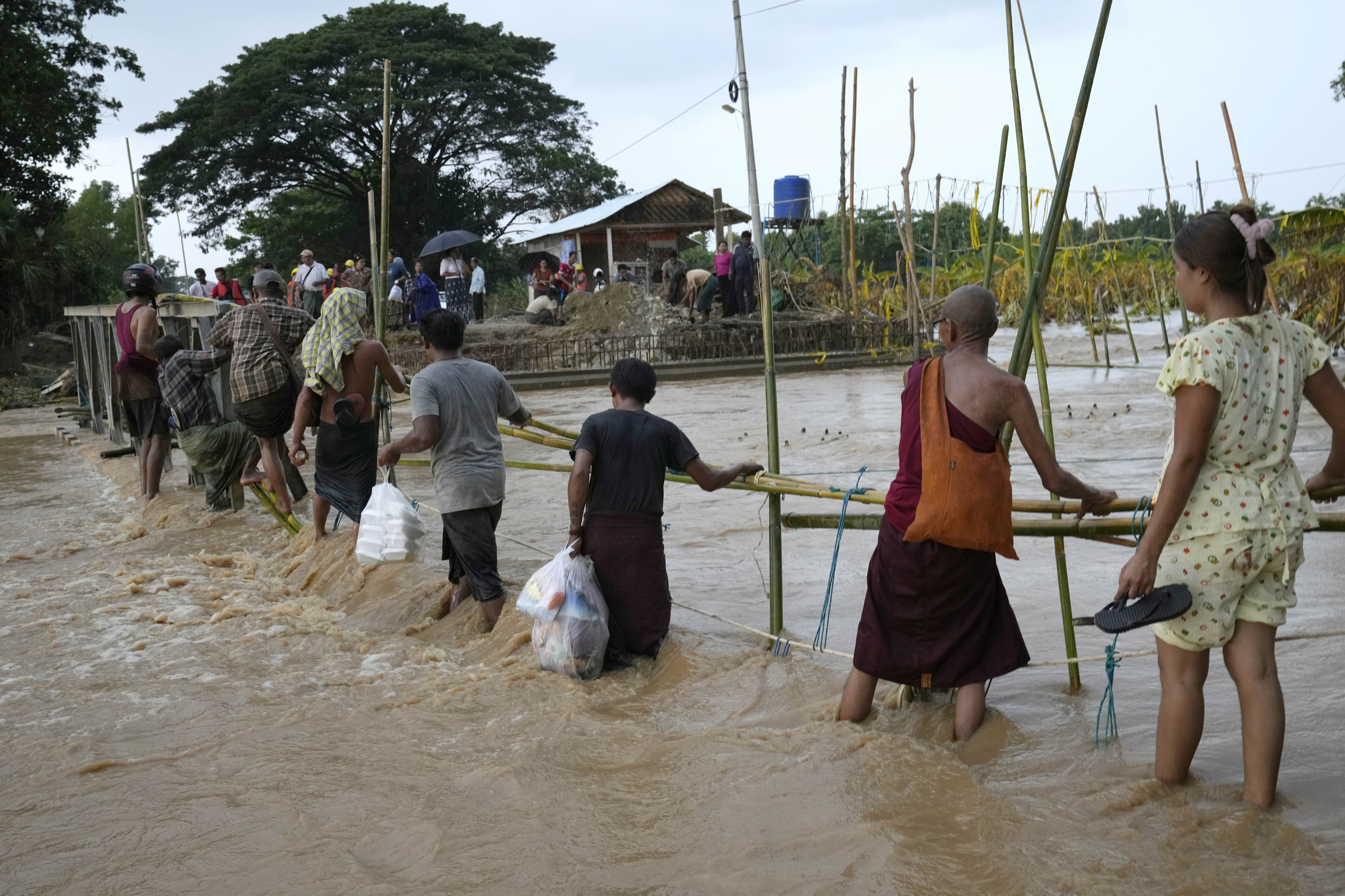 Local residents wade through flooded water at a broken bridge, in Naypyitaw, Myanmar