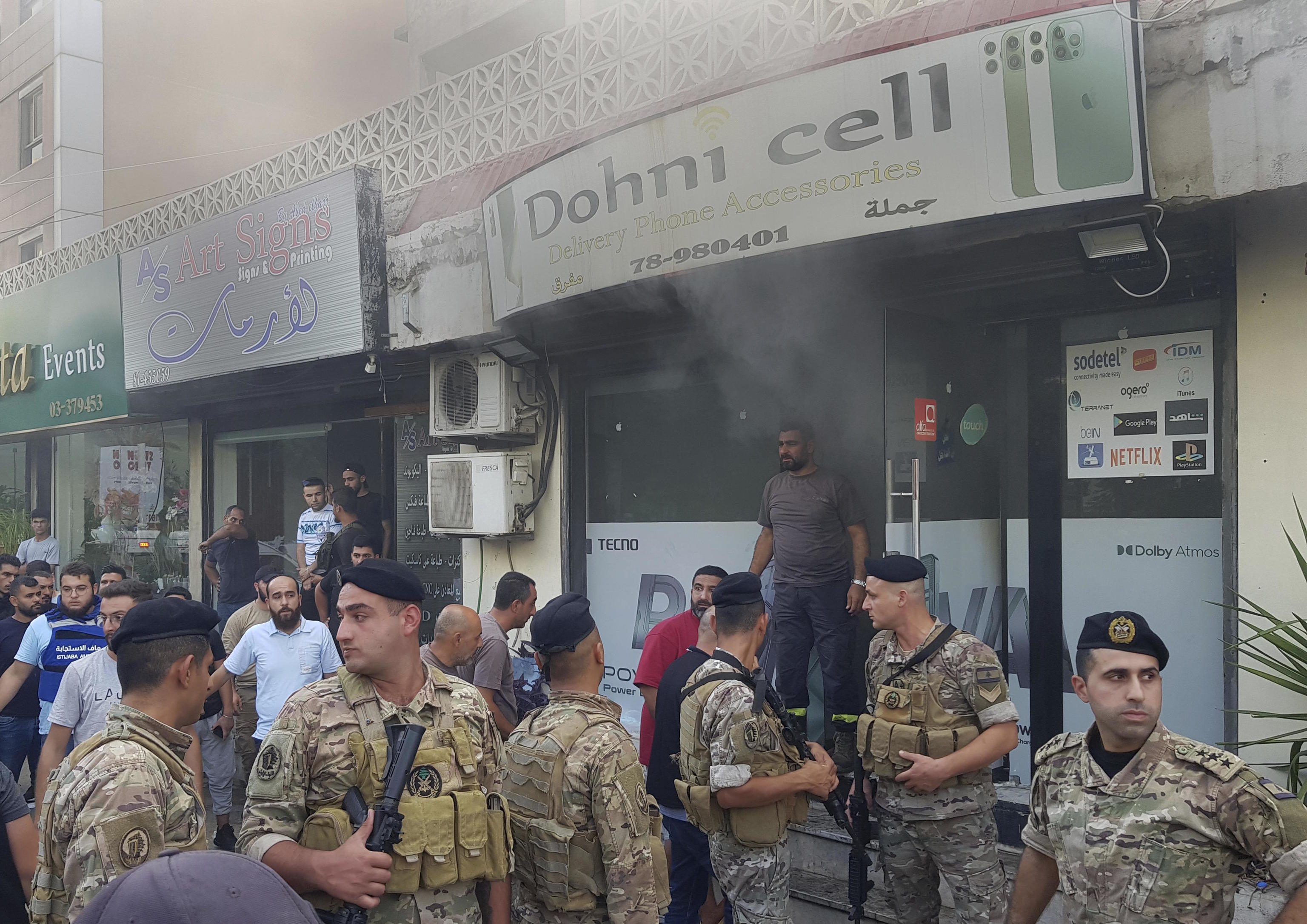 Lebanese soldiers gather outside a damaged mobile shop.