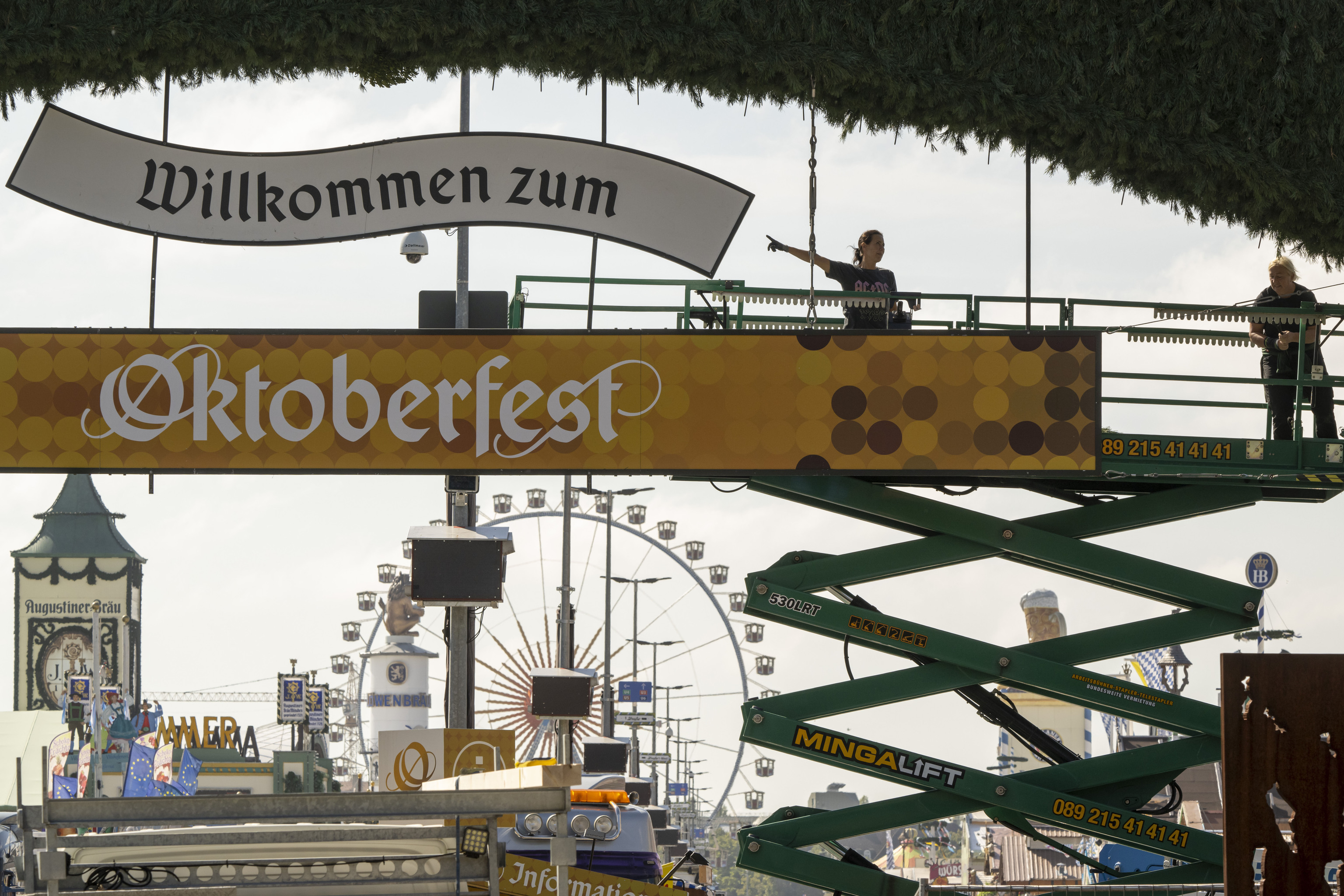 Workers stand on a lifting platform during construction work on the Oktoberfest