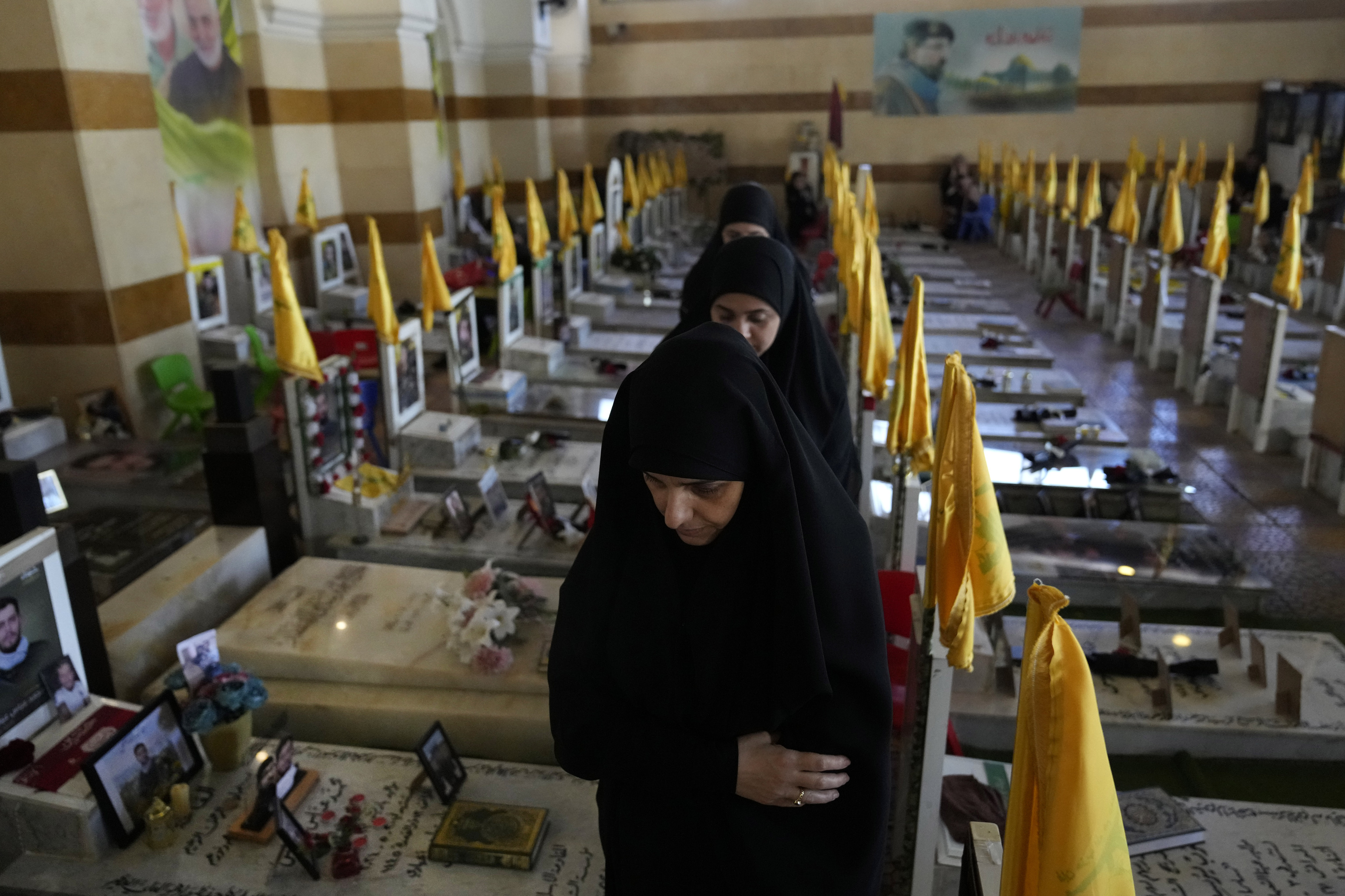 Lebanese Shiite women walk at a cemetery, as they visit the graves of killed Hezbollah members