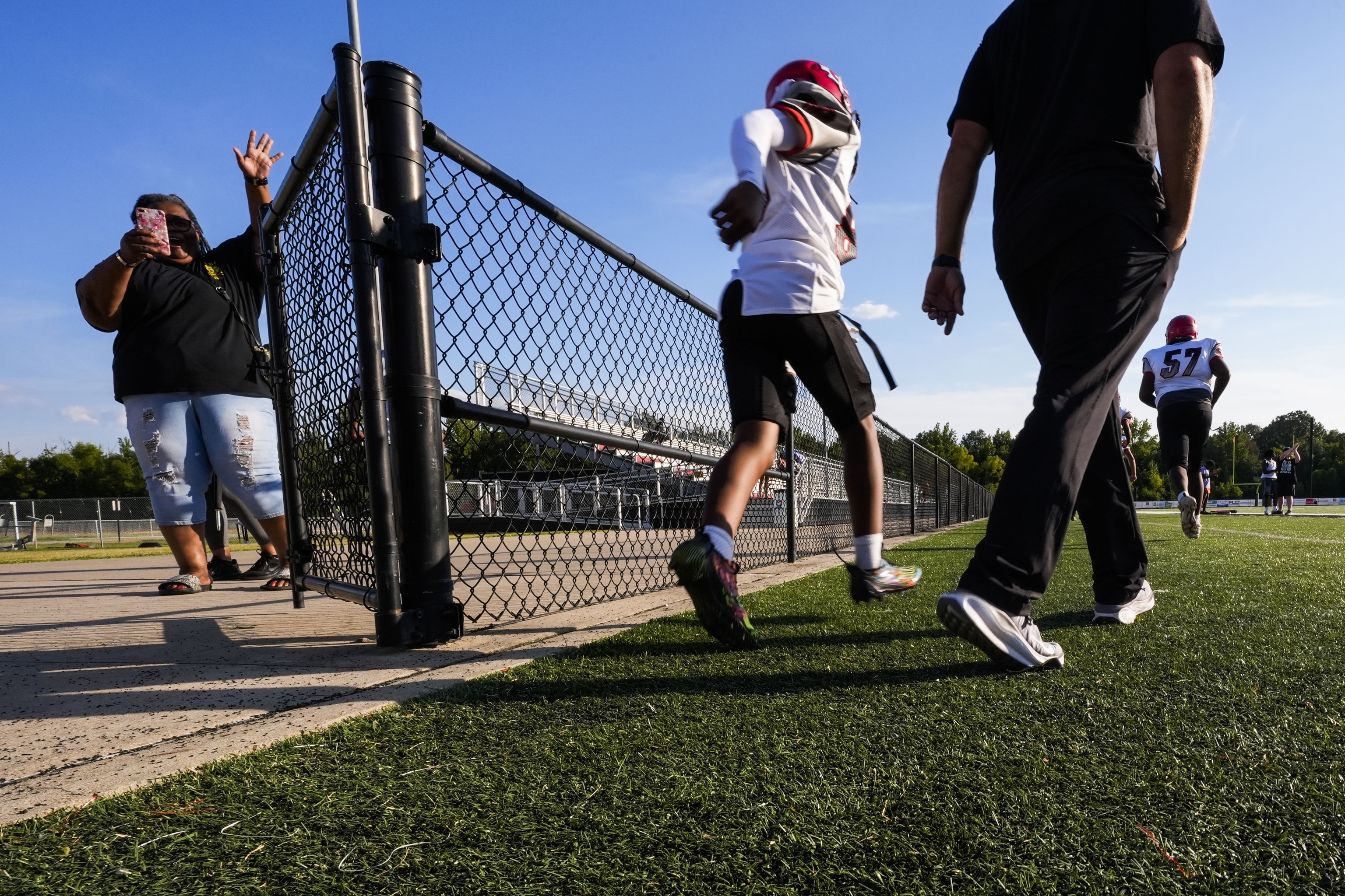 Families wave and take photos as members of the Clinton High School freshman football