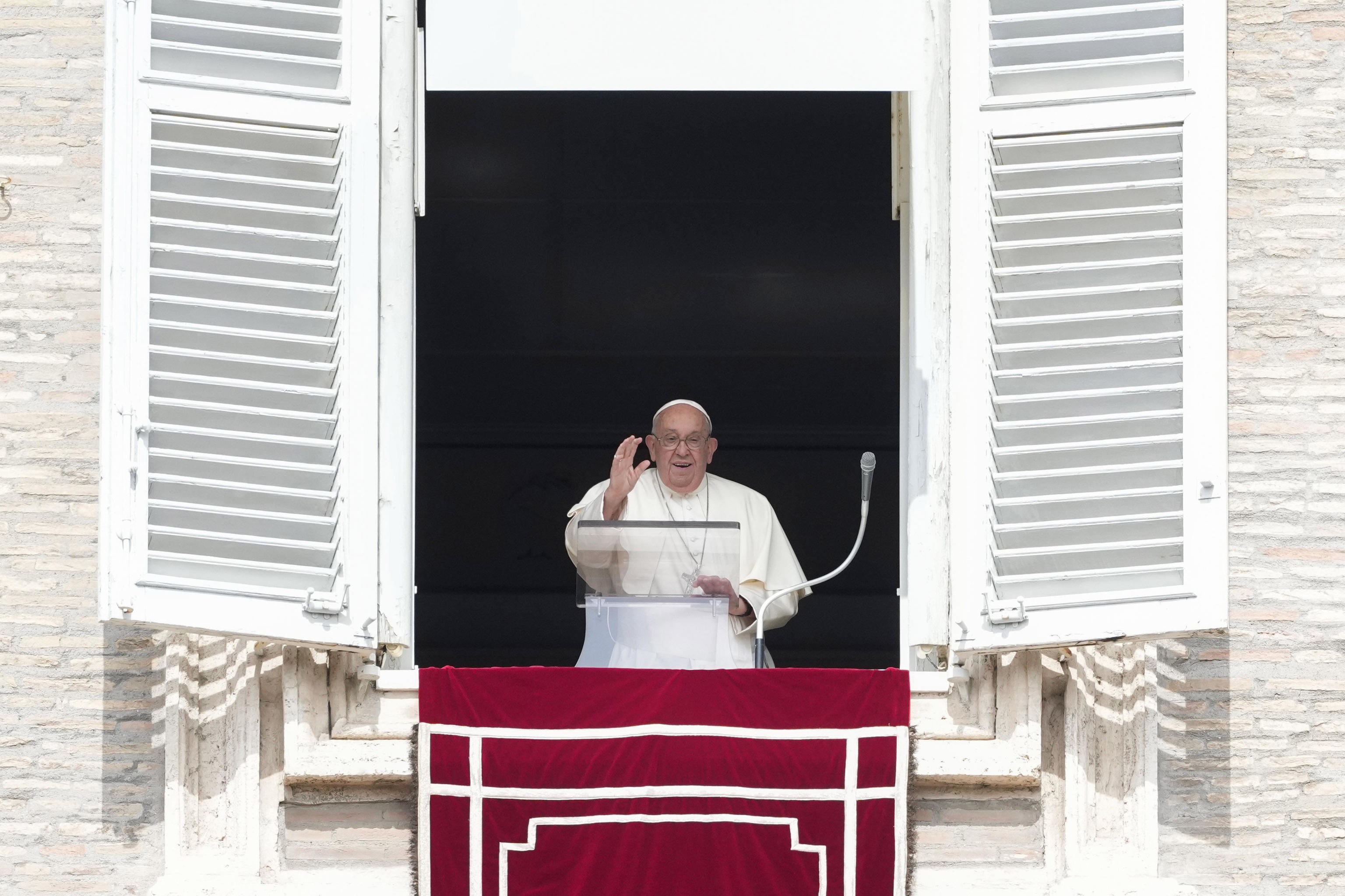 Pope Francis waves during the Angelus prayer.