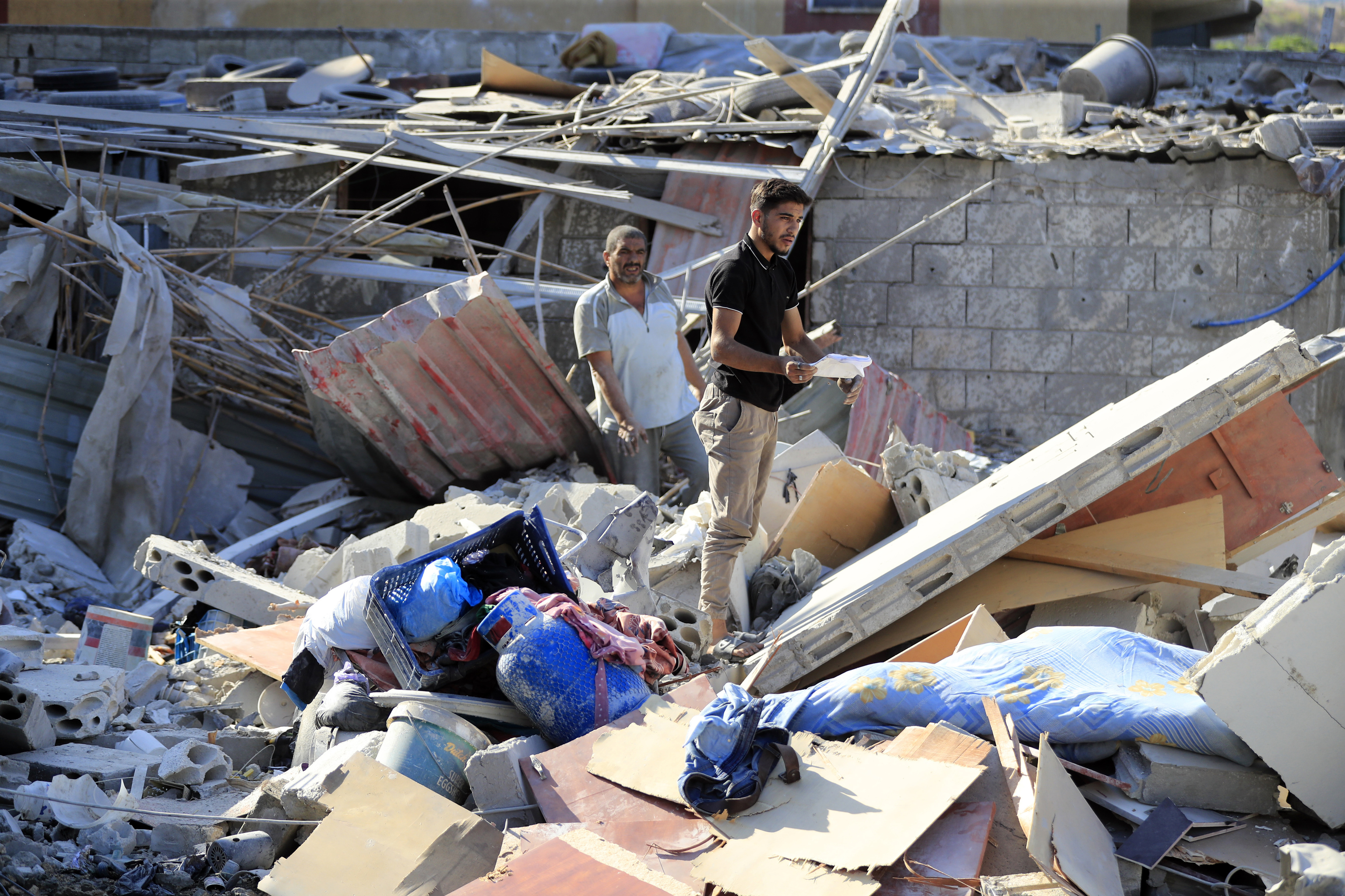 Men stand on the rubble of a building hit in an Israeli airstrike in the southern village of Akbieh, Lebanon