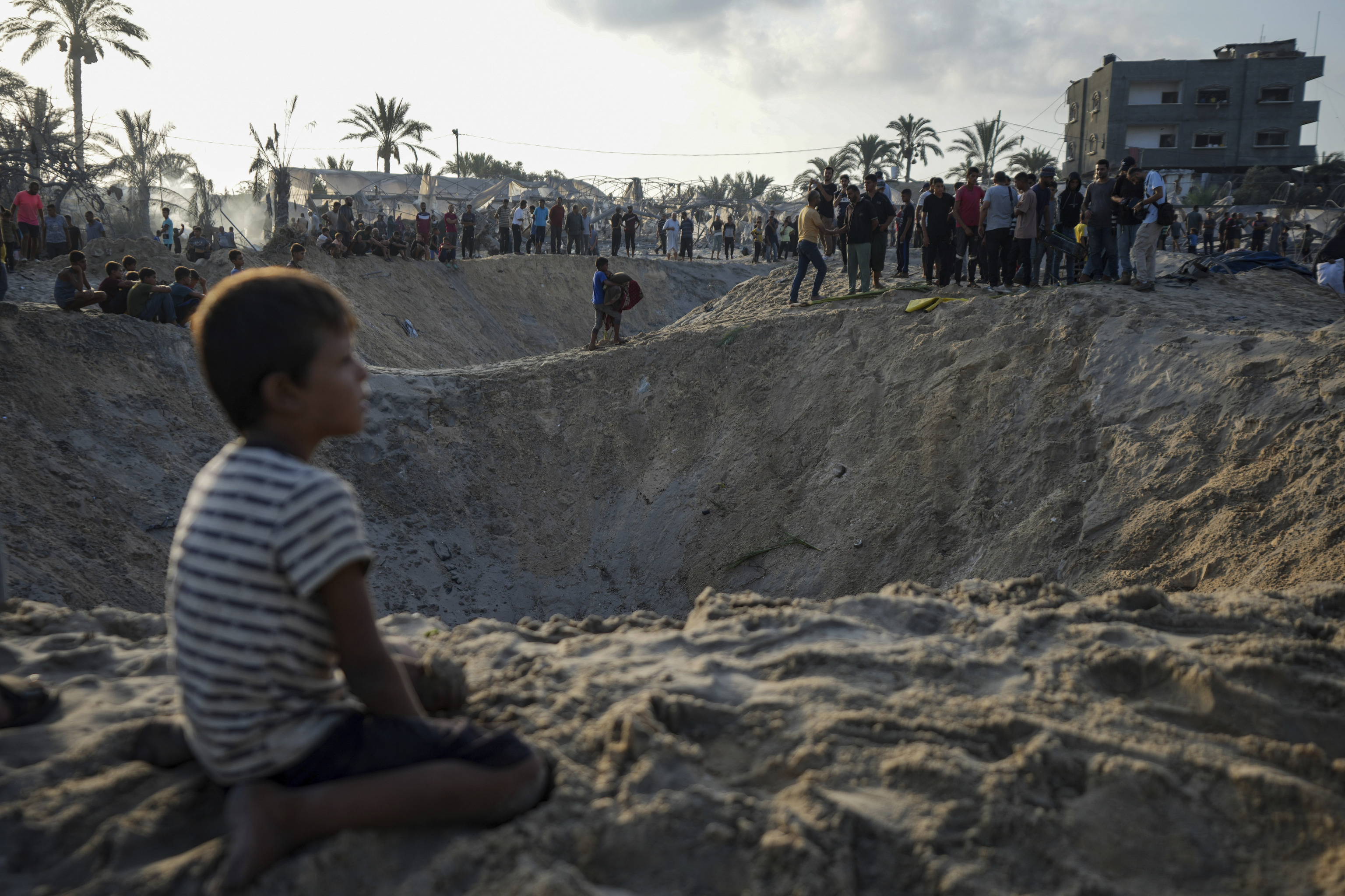 Palestinians look at the destruction after an Israeli airstrike