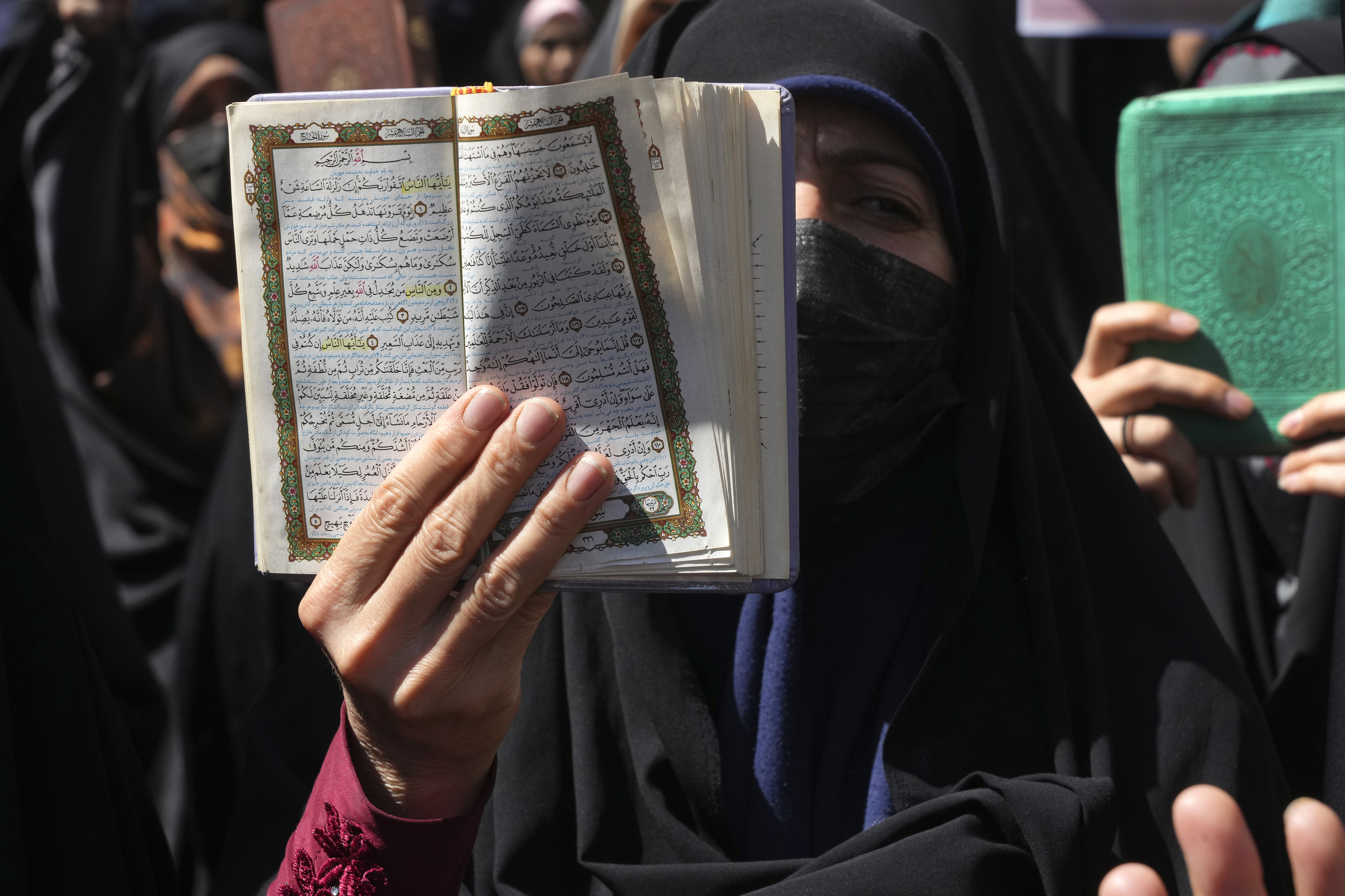 A demonstrator holds up a copy of the Quran, Islam's holy book, during a protest of the burning of a Quran in Sweden