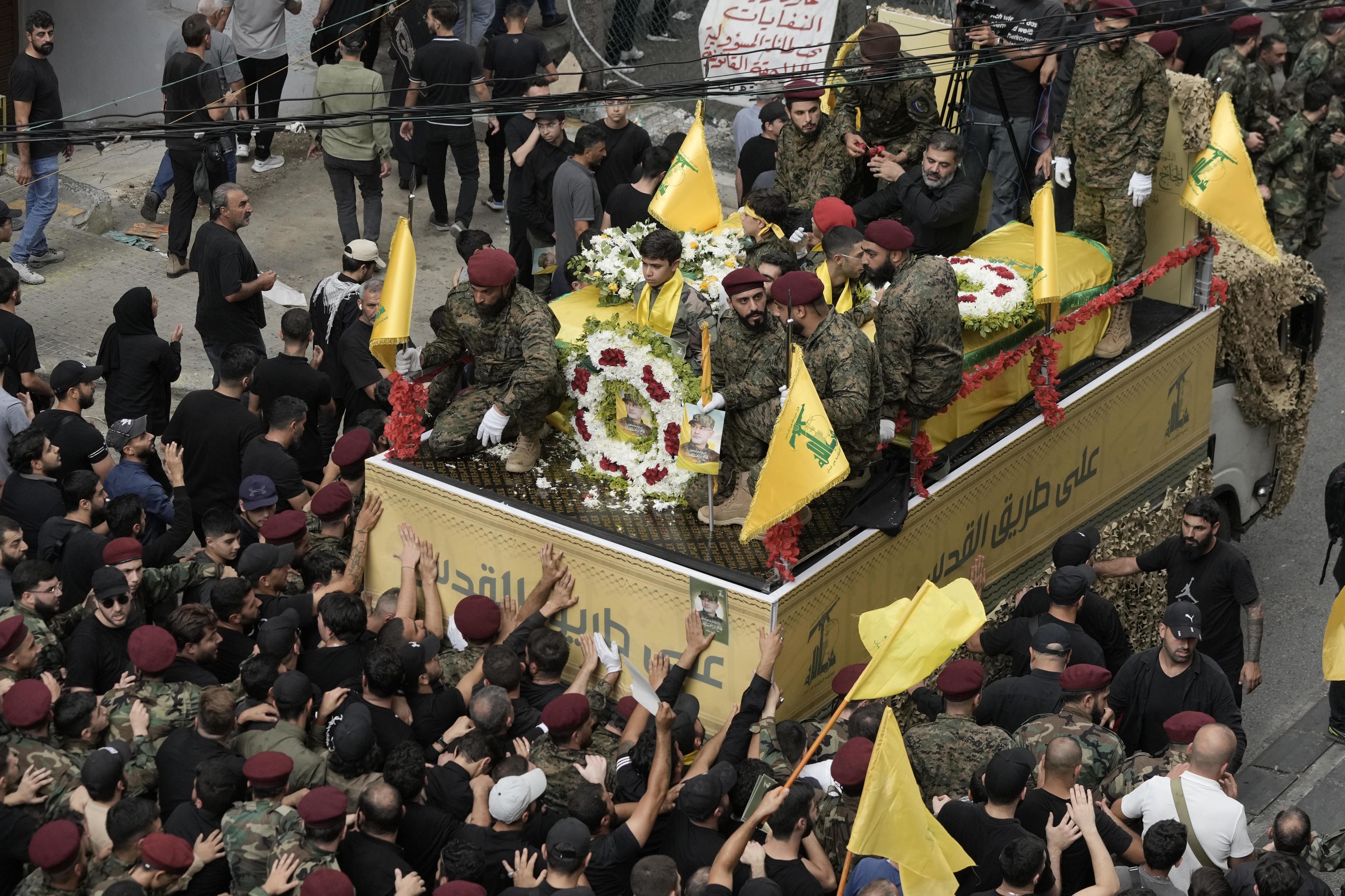 Hezbollah supporters march behind the hearse of Hezbollah commander and militant.