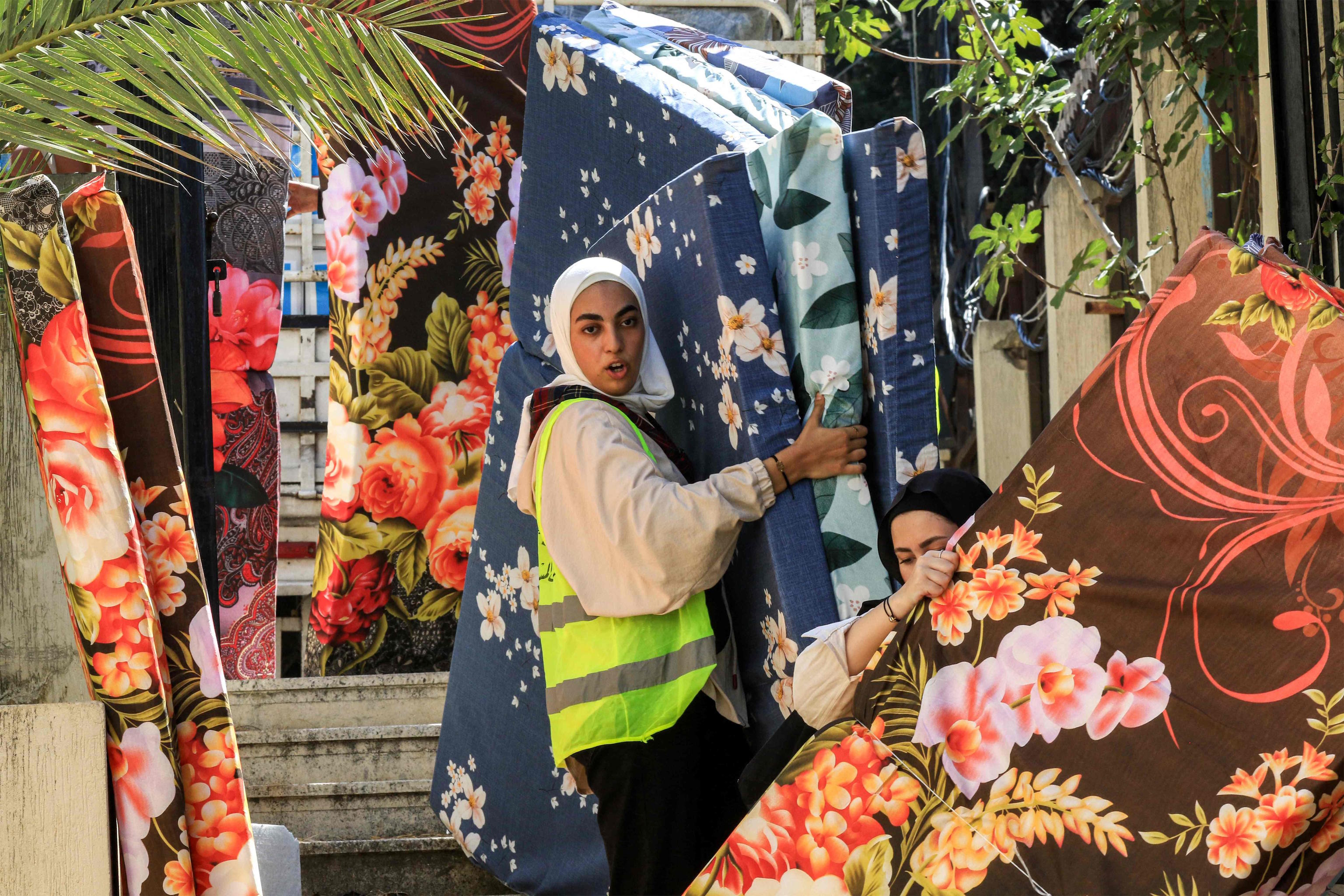 Volunteers transport mattresses for people displaced by conflict from Lebanon.