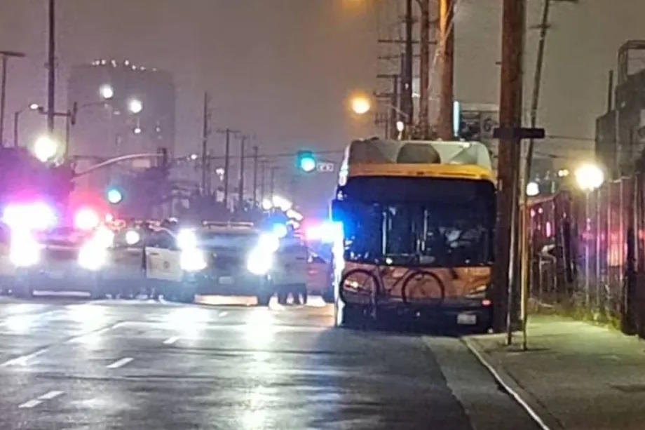 The bus stopped on the side of the road next to the police cars.