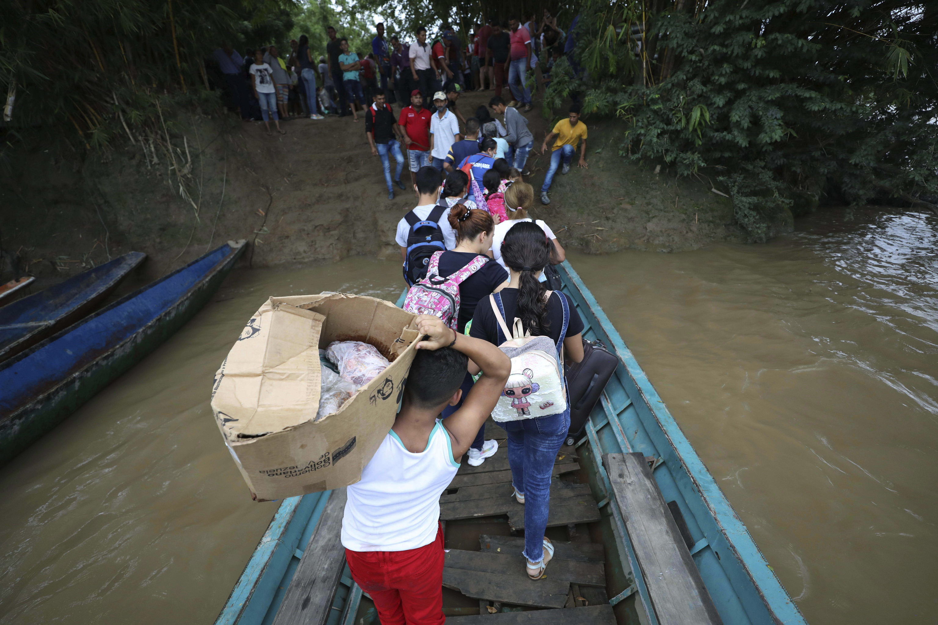 Venezuelans disembark a boat on the Arauca River, the natural border between Venezuela and Colombia