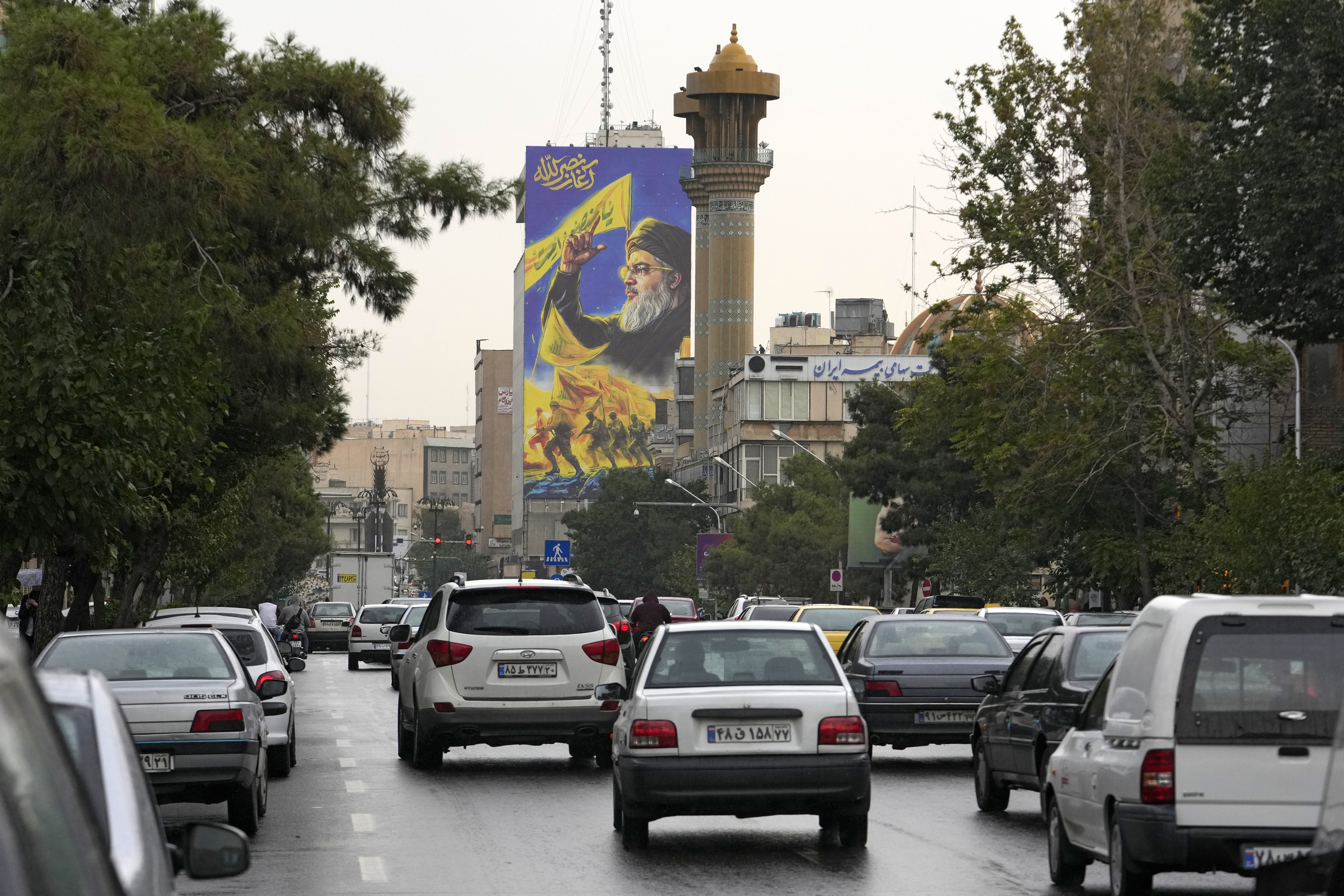 Vehicles drive under a huge portrait of slain Hezbollah leader Hassan Nasrallah.