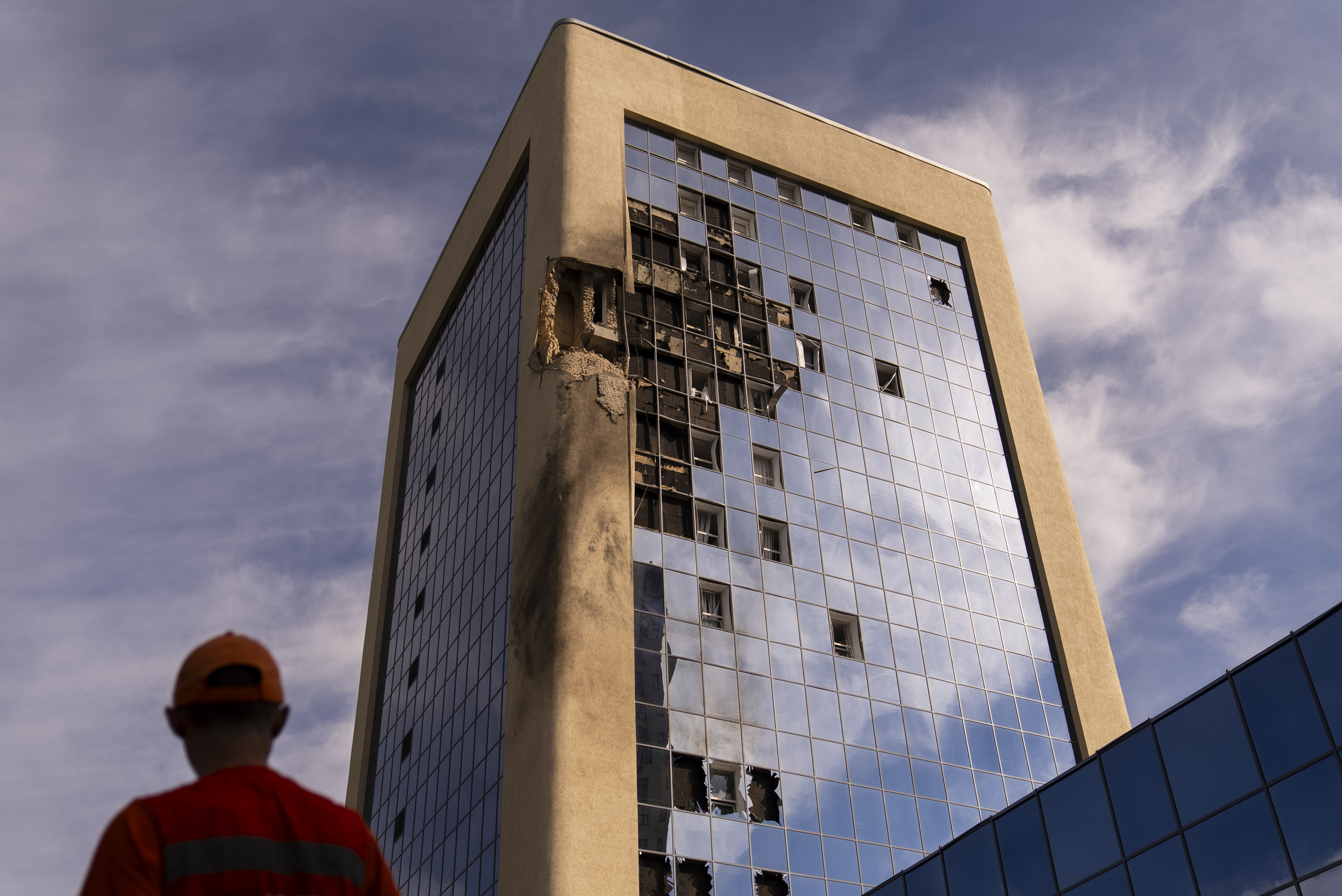 A maintenance worker stands outside a damaged government building in Kyiv,