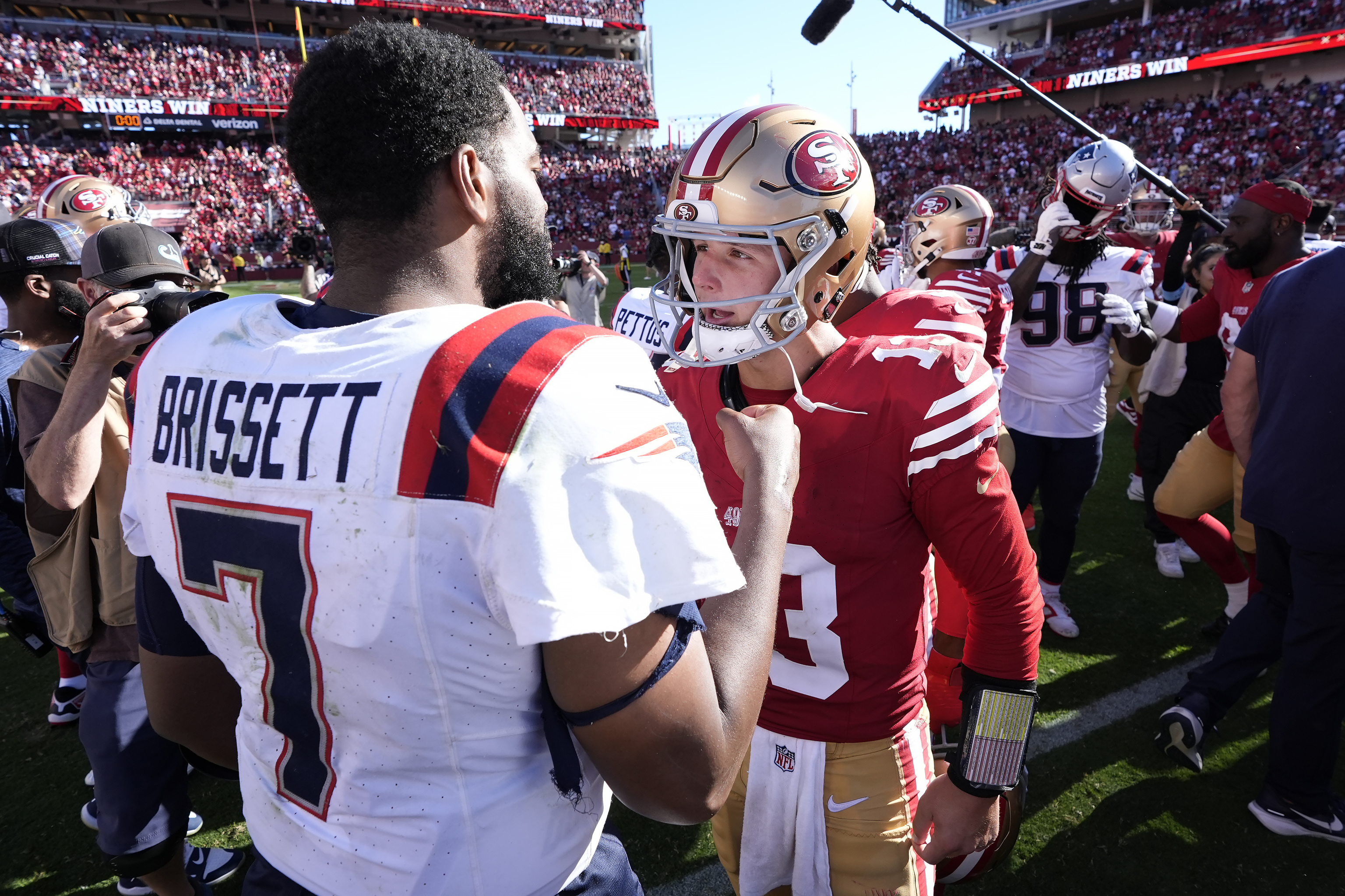 New England Patriots quarterback Jacoby Brissett (7) talks with San Francisco 49ers quarterback Brock Purdy.