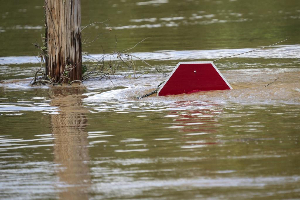 A stop sign is barely visible in floodwaters of a parking.