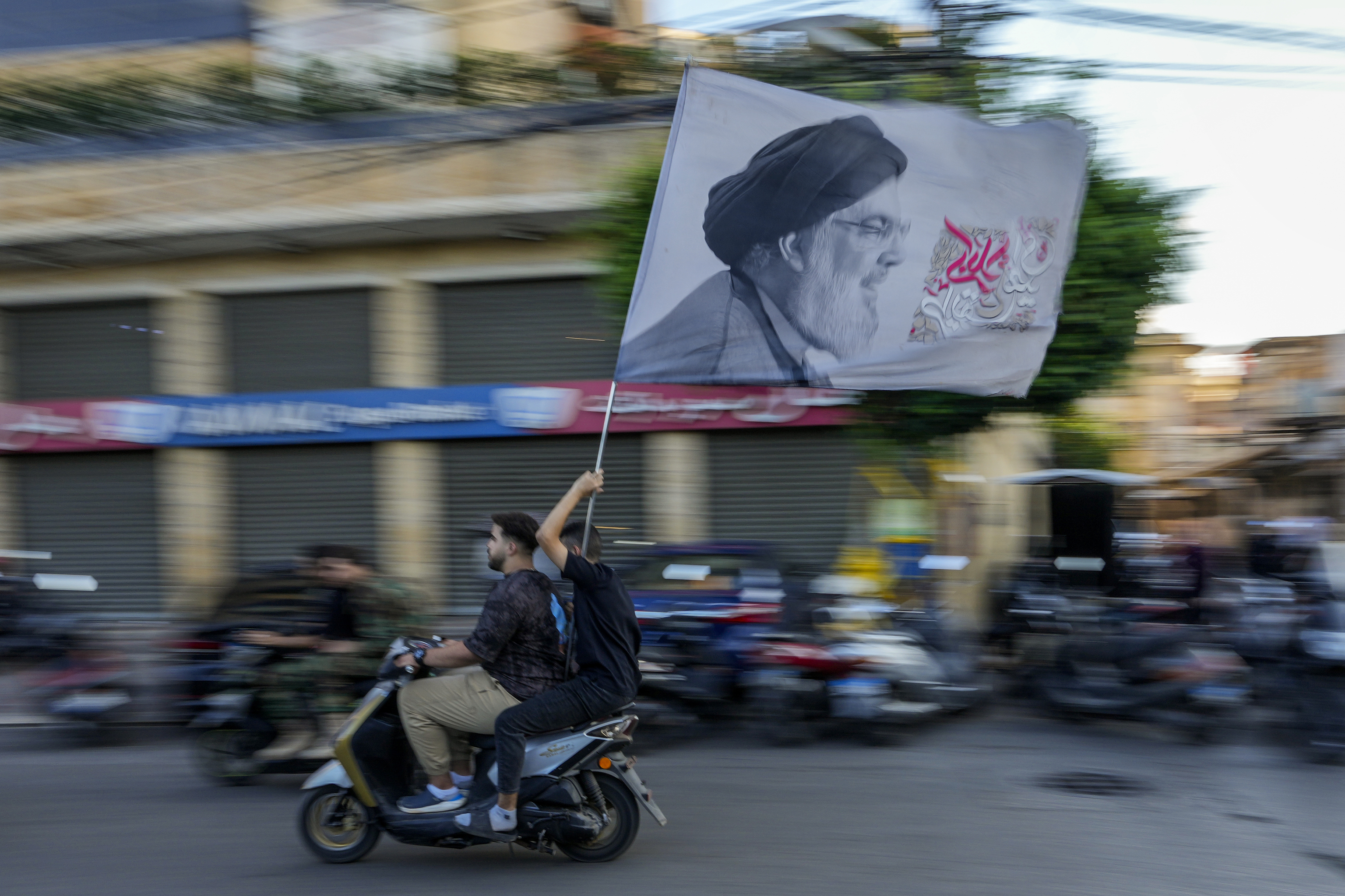 Hezbollah supporters carry a flag depicting Hezbollah leader Hassan Nasrallah