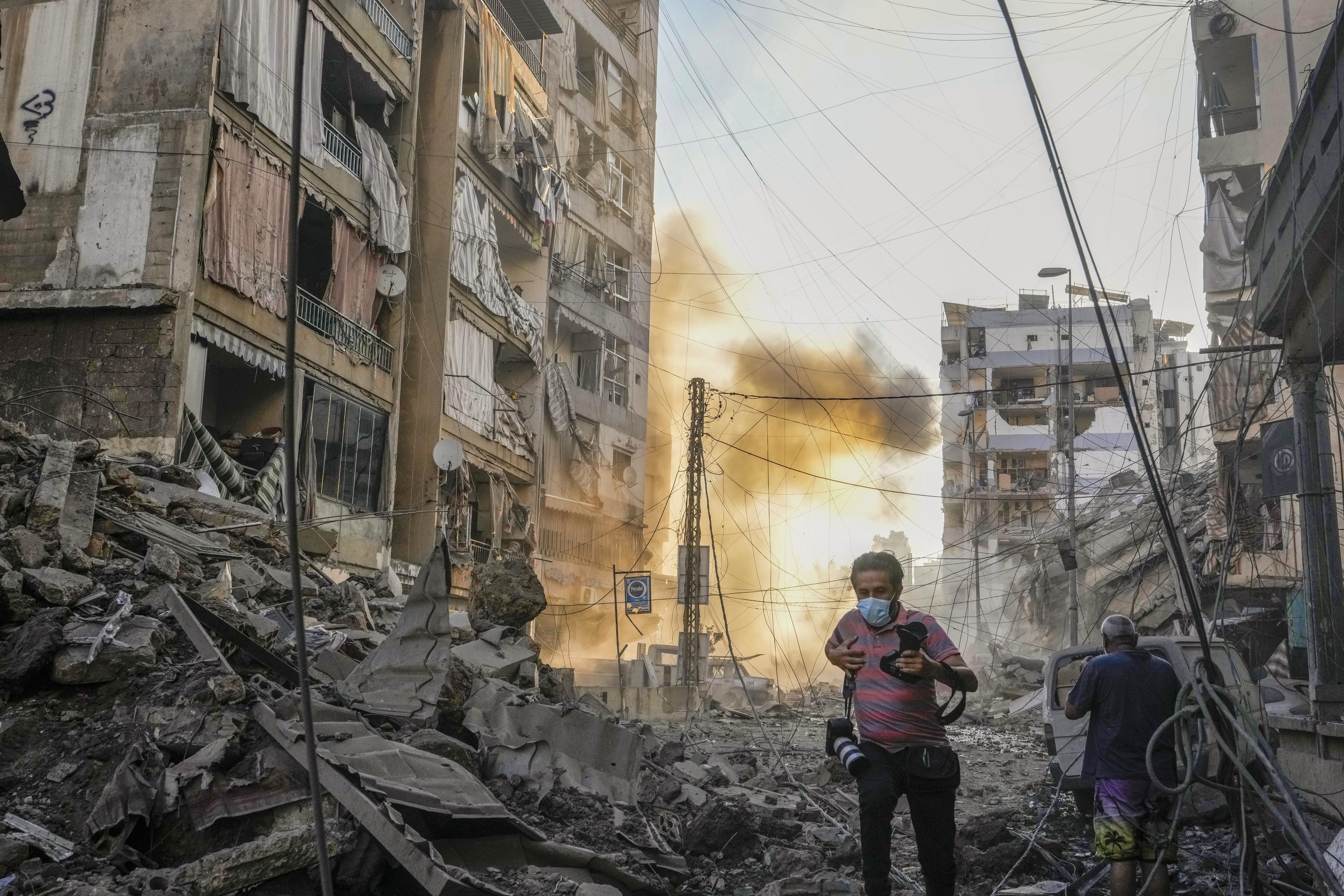 A photographer runs for cover following an Israeli airstrike in Dahiyeh, Beirut.