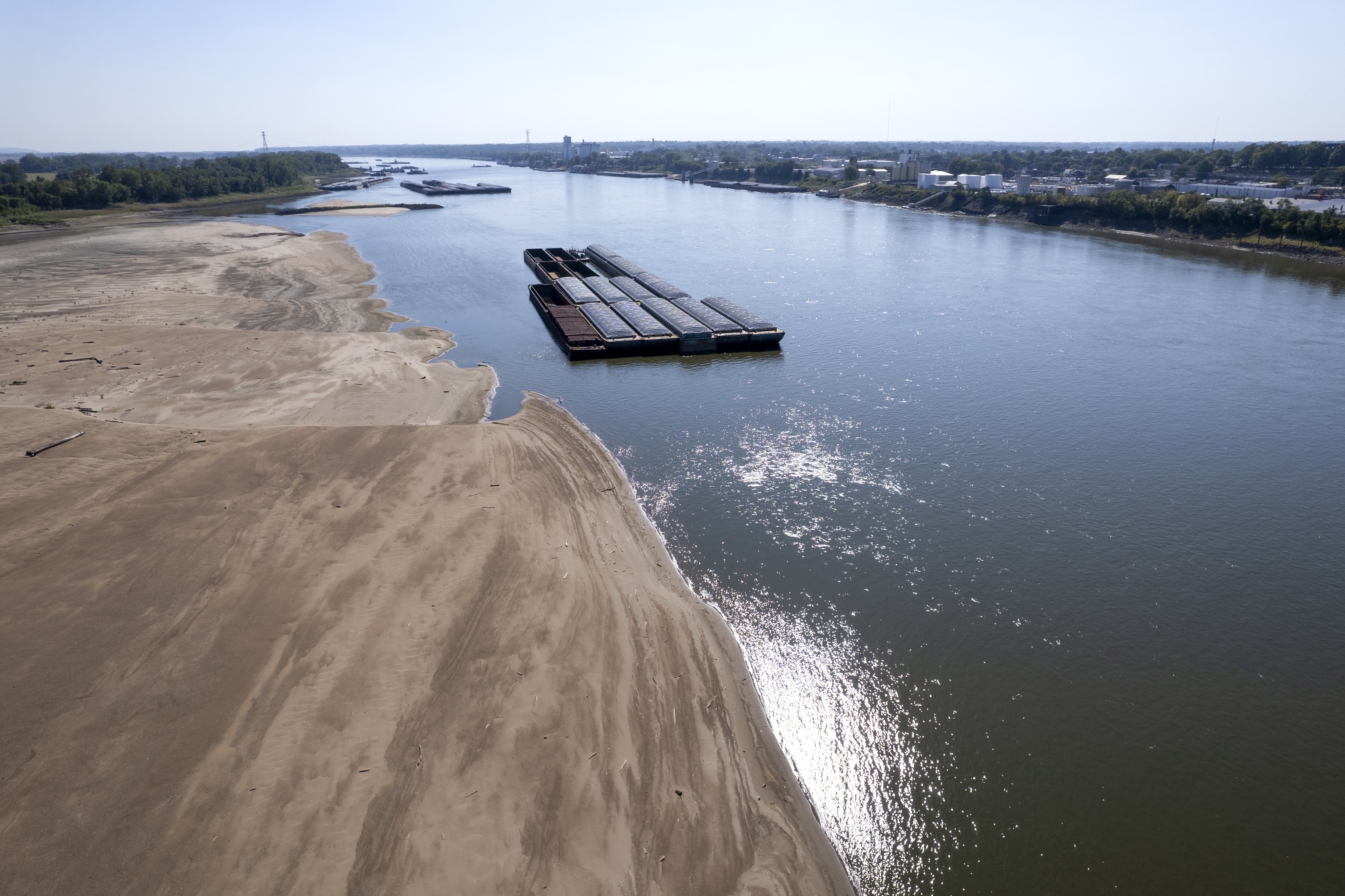 Barges float in the Mississippi River as a portion of the riverbed is exposed