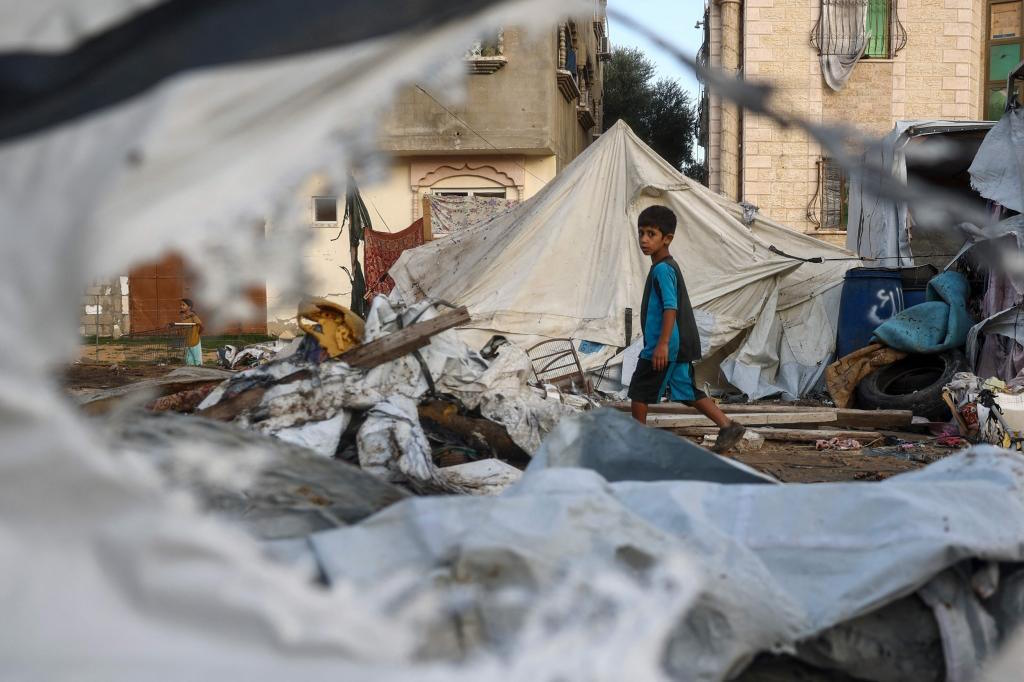 A child walks next to destoyed tents following an Israeli air strike.