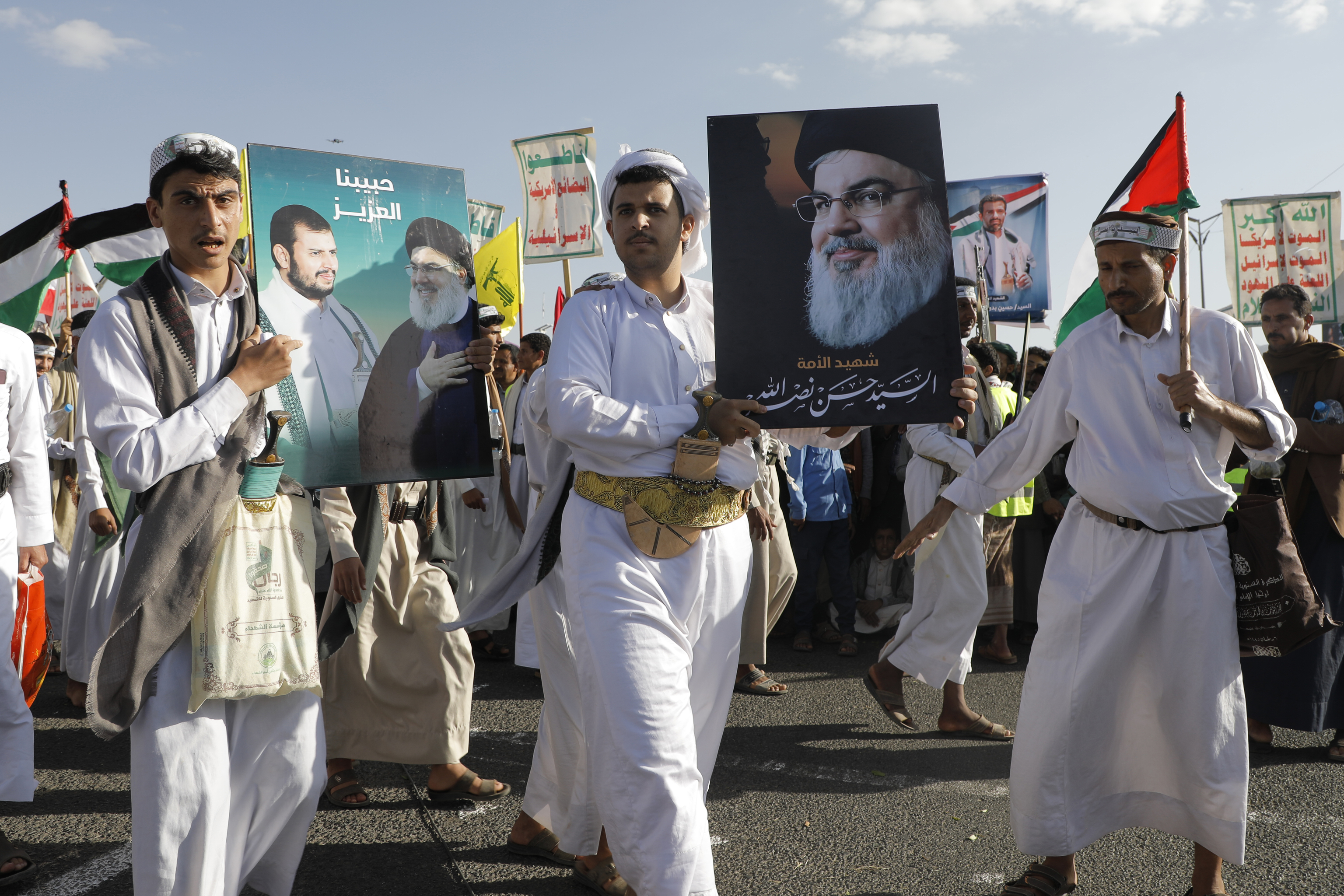 Houthi supporters raise a poster of the late Hezbollah leader Hassan Nasrallah