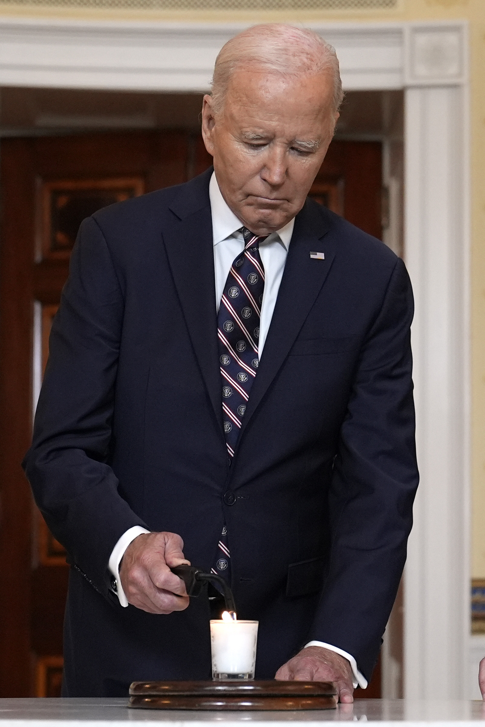 President Joe Biden lights a memorial candle in the Blue Room of the White House in Washington