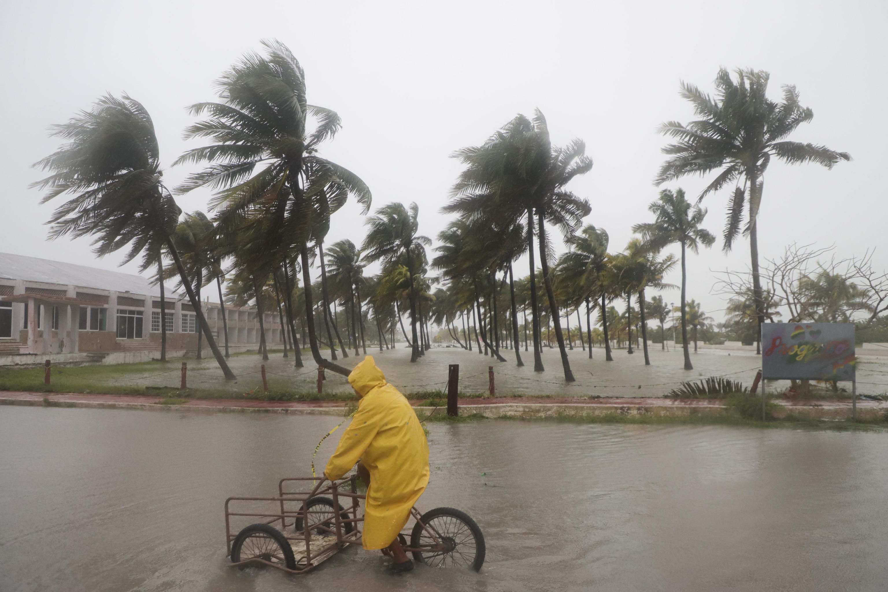 A person rides his bike through a flooded street in the rain in Yucatan state.