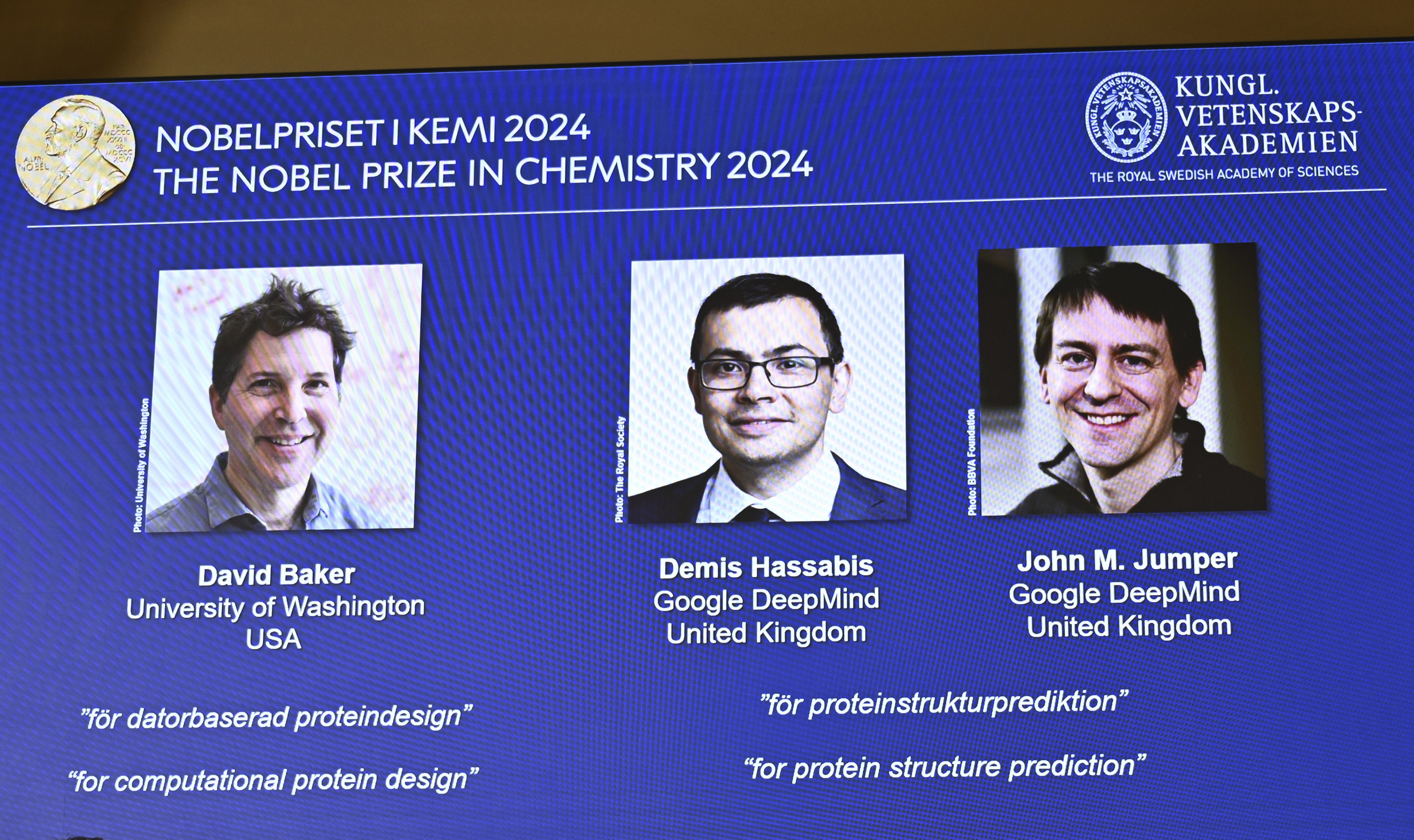 An image of a screen showing the winners of this years Nobel Prize in Chemistry, David Baker, Demis Hassabis, and John M Jumper