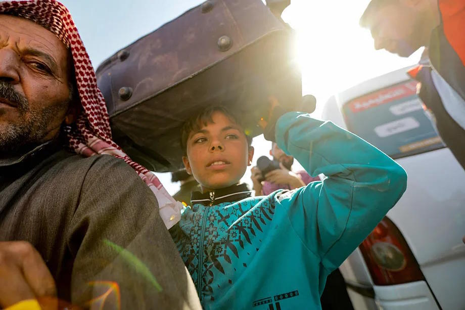 A child carries a suitcase as Syrian refugees in Lebanon return to their home country.