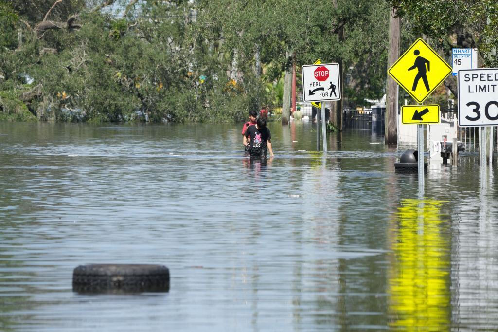 Children walk in the water as the streets are flooded in Tampa.