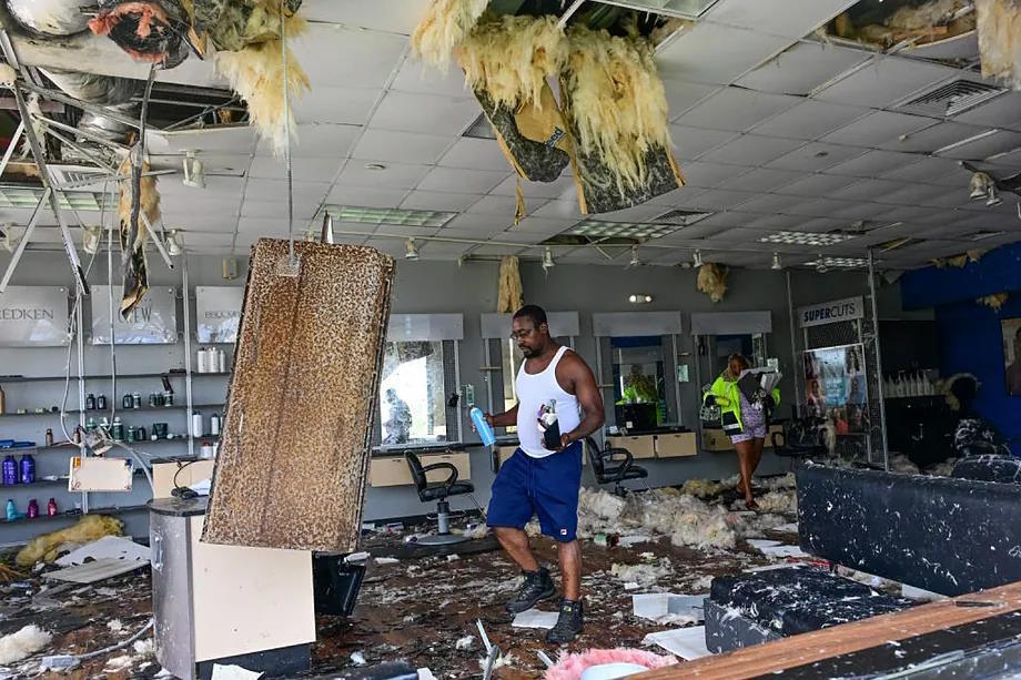 Employees gather some of their belongings from a beauty salon destroyed by Milton.