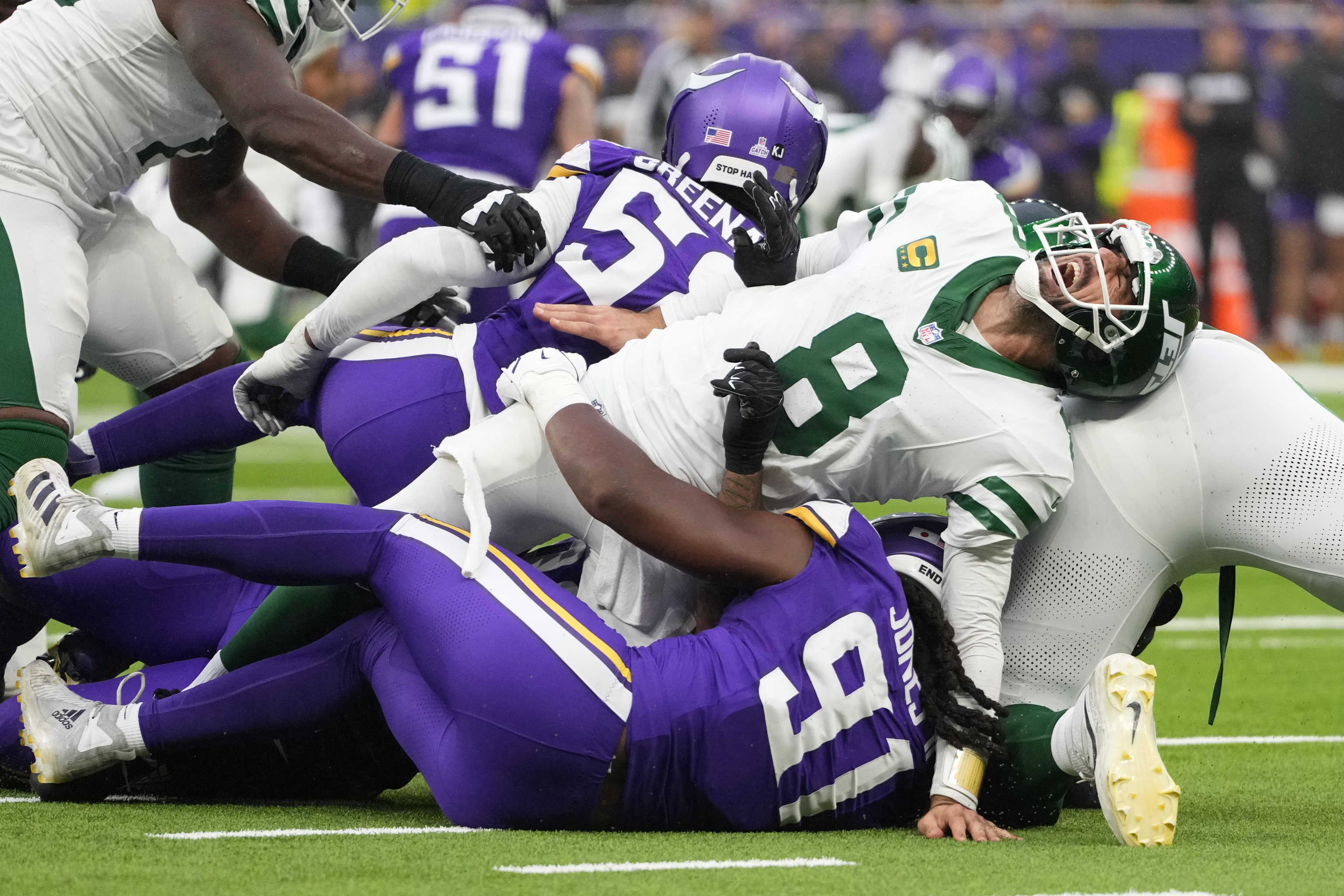 New York Jets quarterback Aaron Rodgers (8), right, reacts as he is tackled during the second half of an NFL football game against the Minnesota Vikings,