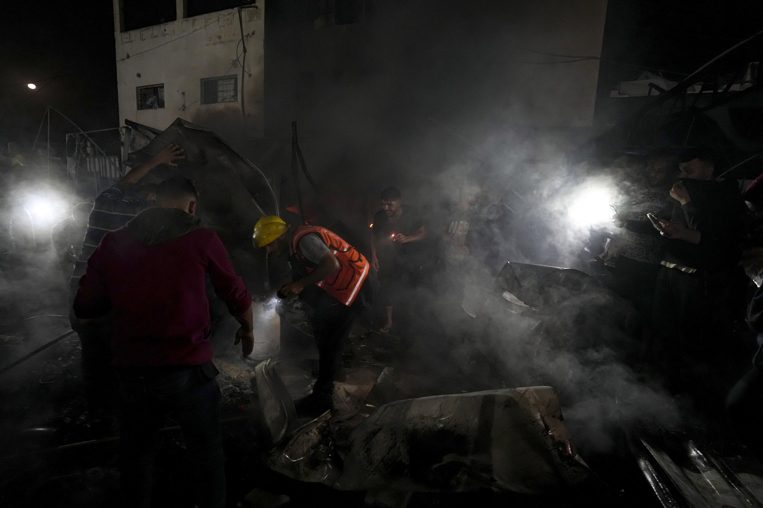 Palestinians try to put out the fire caused by an Israeli attack on hospital.