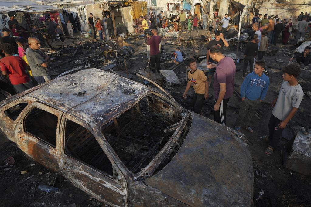 Palestinians look at the damage after an Israeli strike hit a tent area in the courtyard of Al Aqsa Martyrs hospital in Deir al Balah