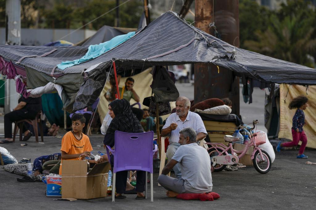 Families fleeing Israeli airstrikes in the south, sit in Martyrs' square