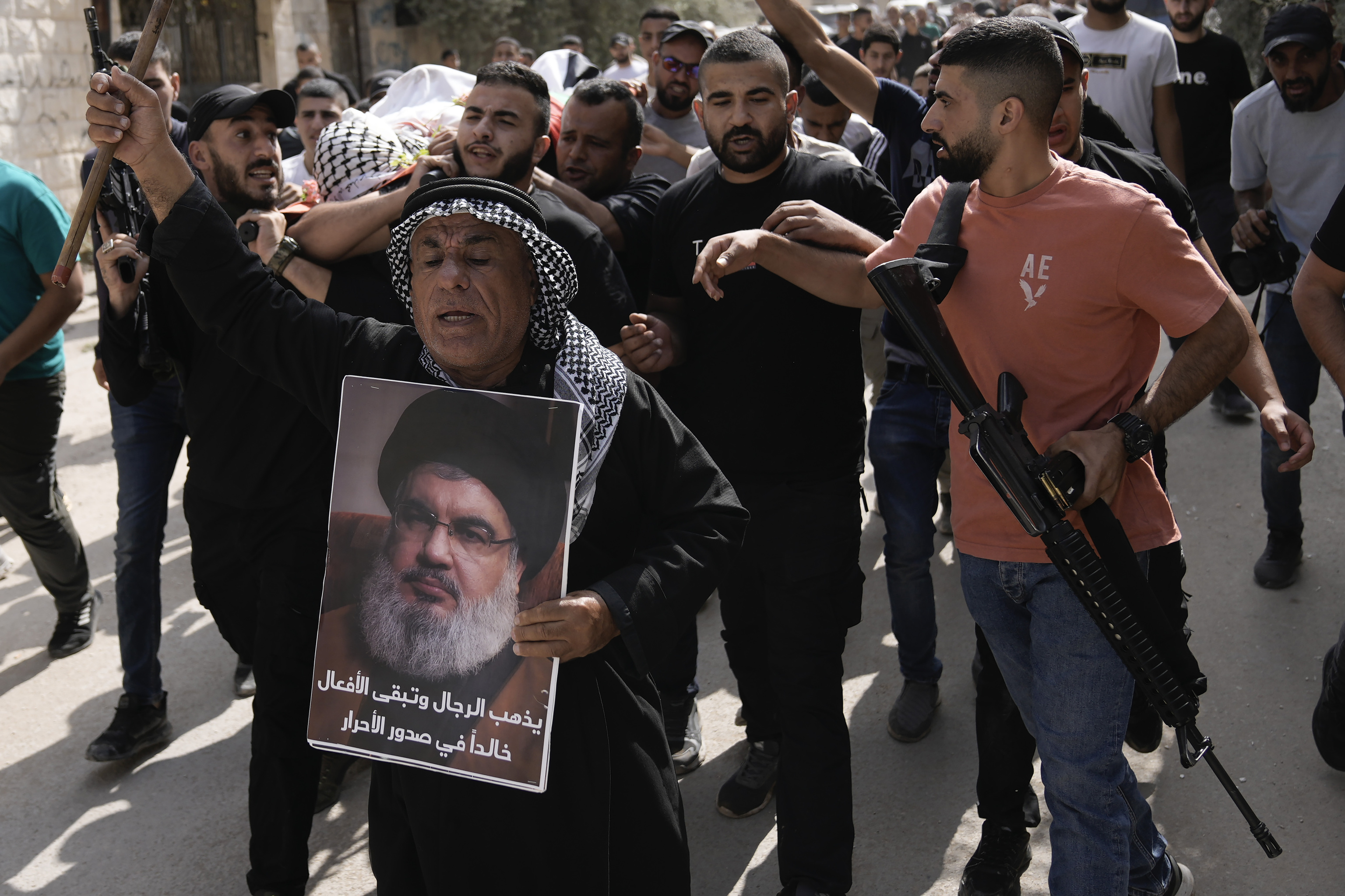 Palestinian activist Khairi Hanoun holds up a poster of Hassan Nasrallah, the leader of Hezbollah who was killed by an Israeli strike