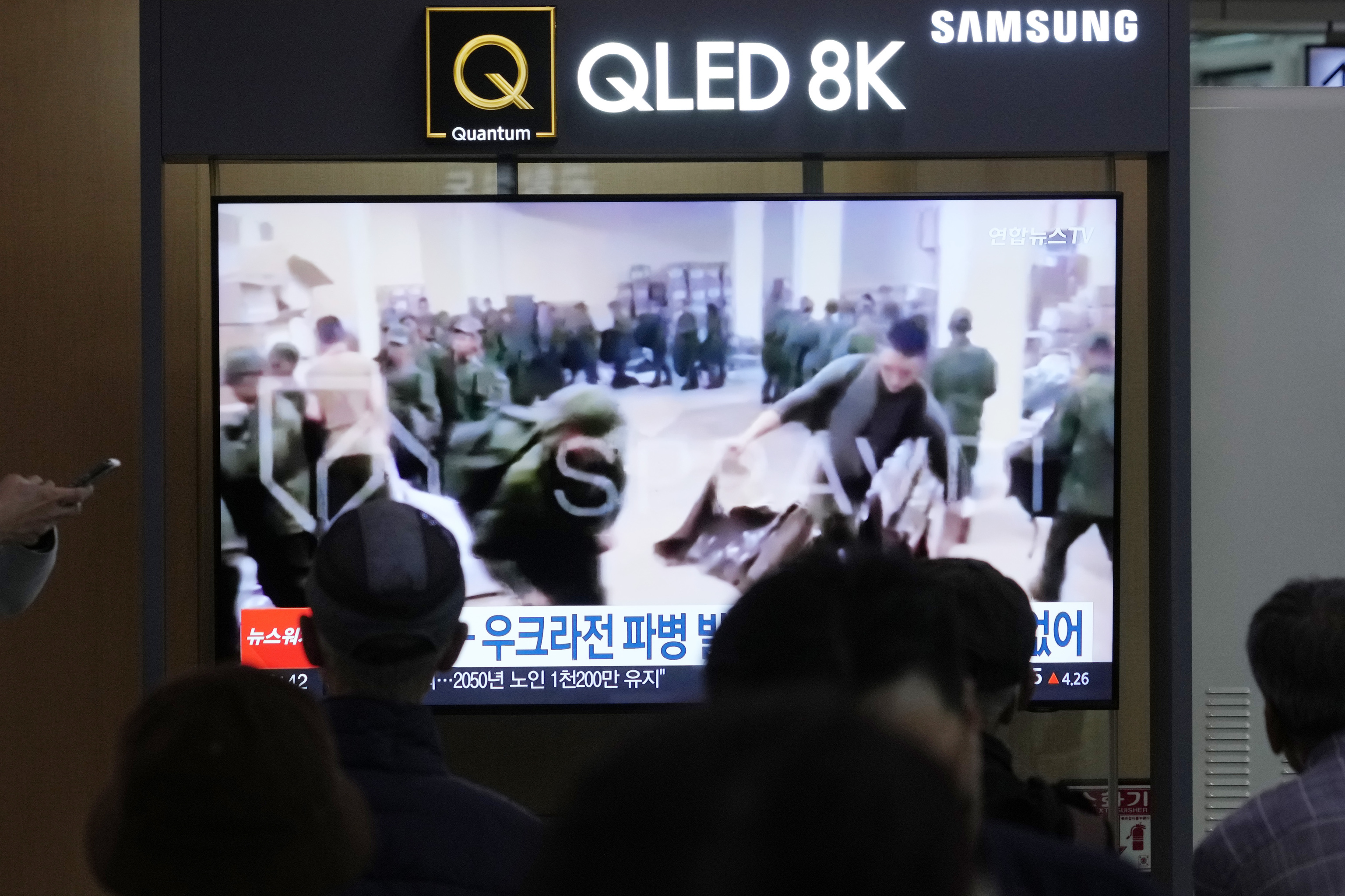 A TV screen shows an image of soldiers believed to be from North Korea stand in line to receive supplies from Russia