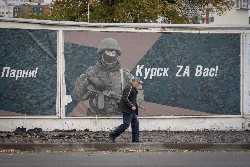 A man walks past a wall adorned with posters honoring Russian soldiers.